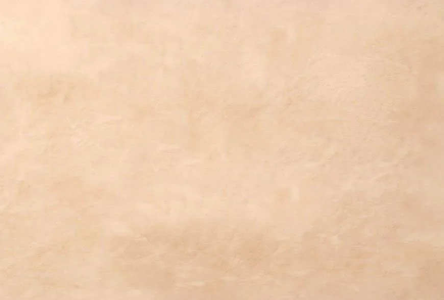 Close-up of a beige or light tan textured surface, possibly a wall or fabric.