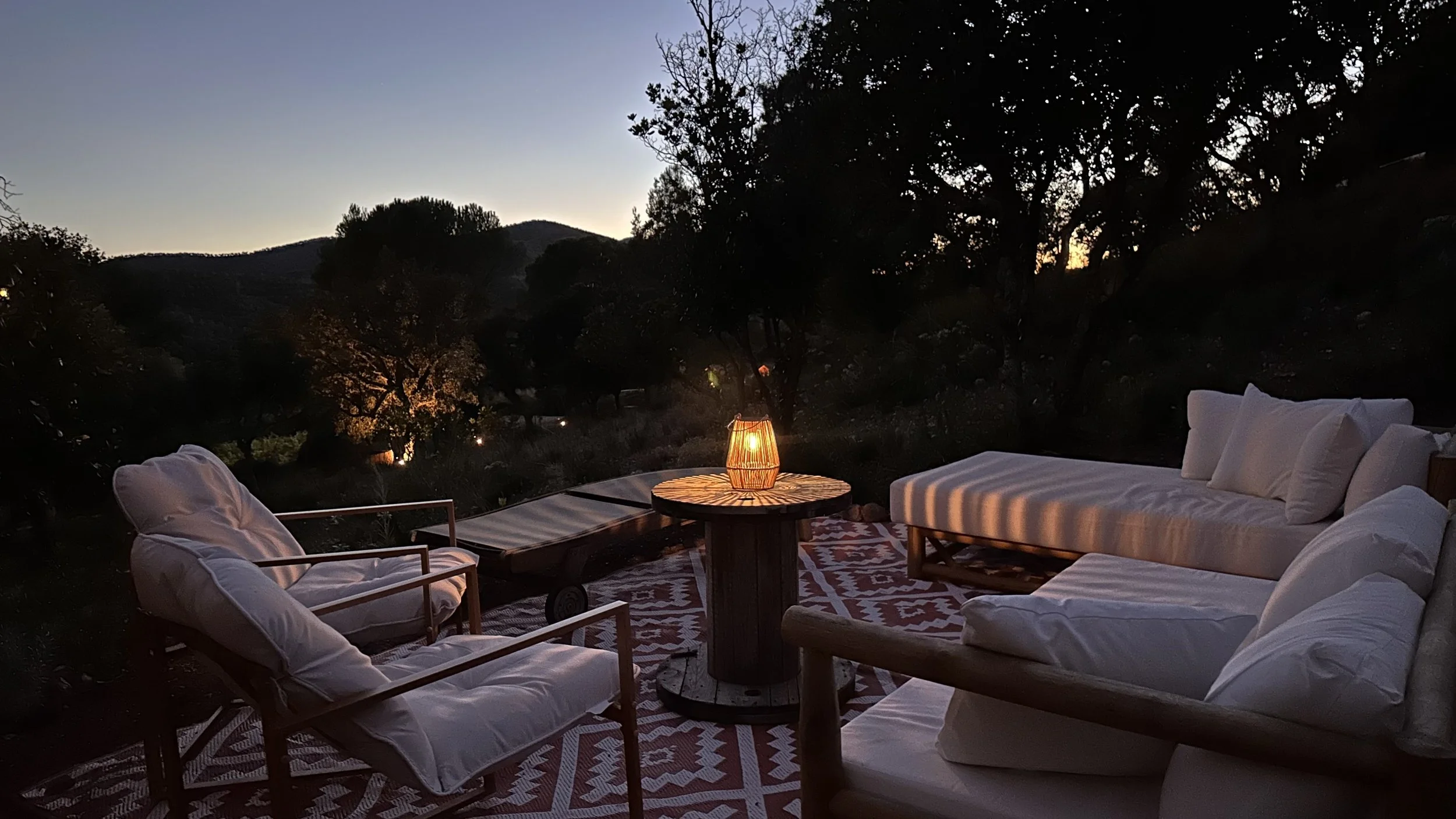 Espace de vie extérieur et zone de détente avec salon de jardin, éclairage doux et vue sur les collines, au cœur d’un lieu de retraite en Provence.