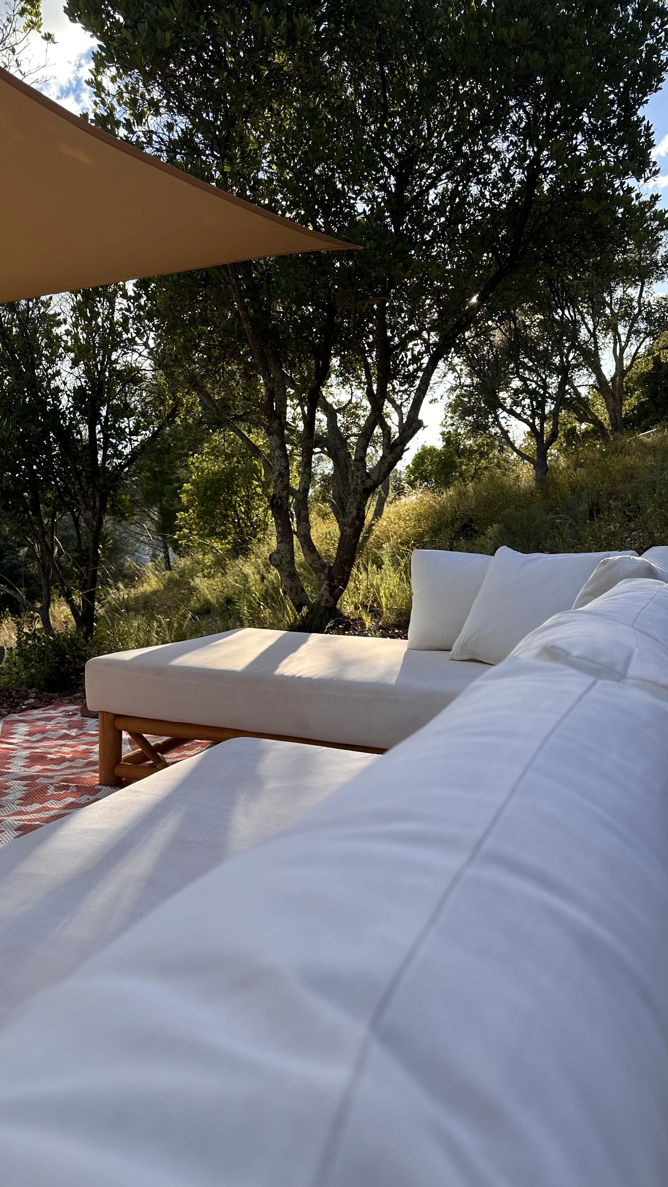 Espace commun ombragé avec banquettes confortables au cœur de la nature, conçu comme un coin détente pour échanger, lire et se reposer lors des retraites de yoga chez Origins Yoga.