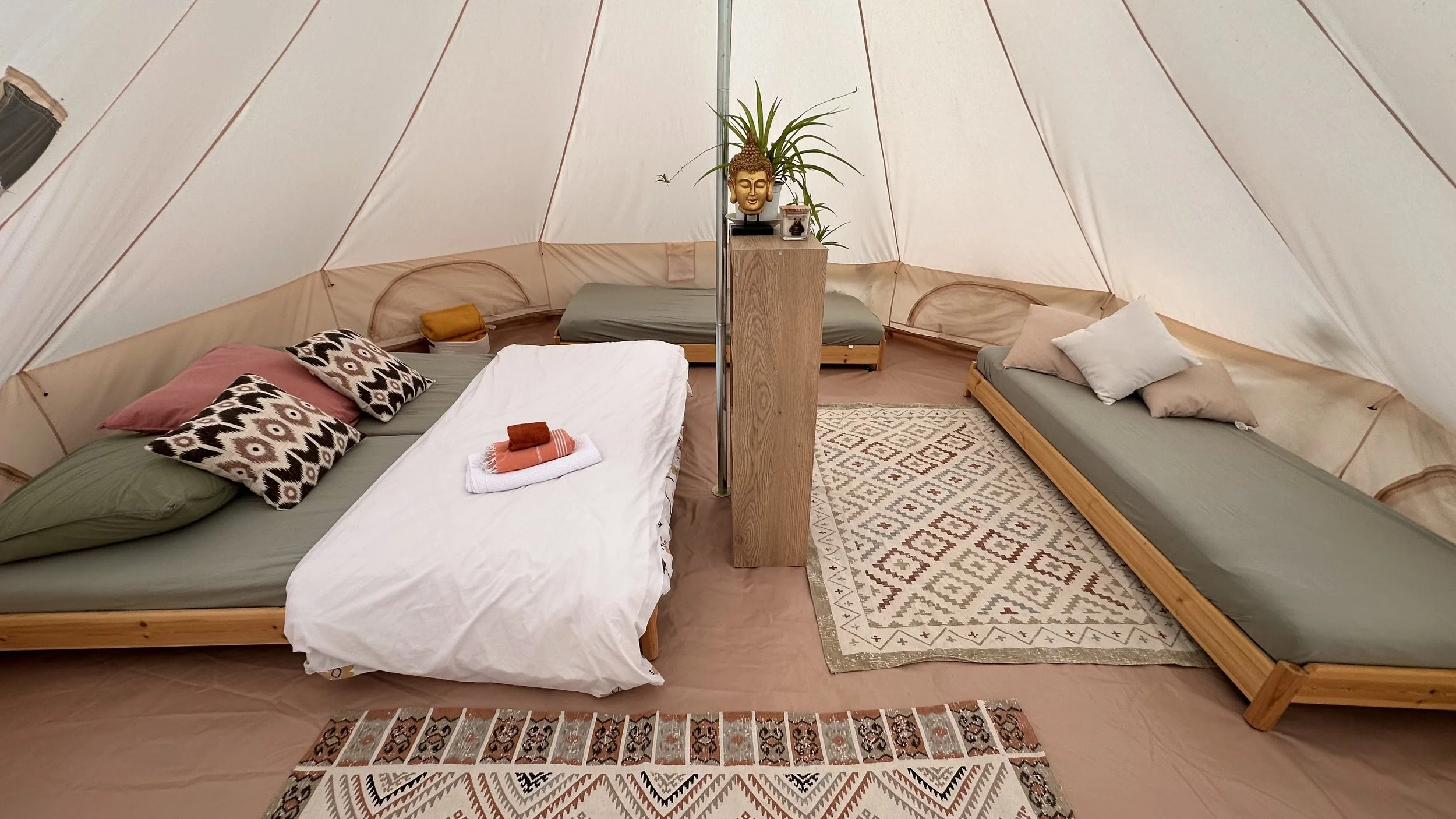 Hébergement en tente lodge confortable avec lits simples, tapis et décoration naturelle, pour retraite de yoga en pleine nature en Provence.