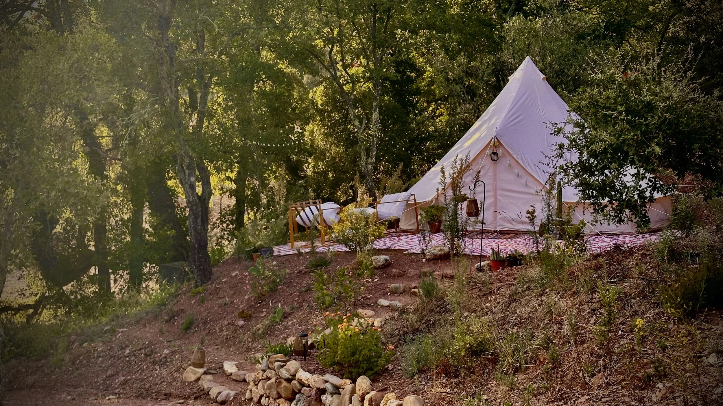 Tente d’hébergement installée sur une terrasse naturelle, au cœur de la forêt, illustrant le cadre calme et isolé dans lequel se déroulent les séjours Origins Yoga.