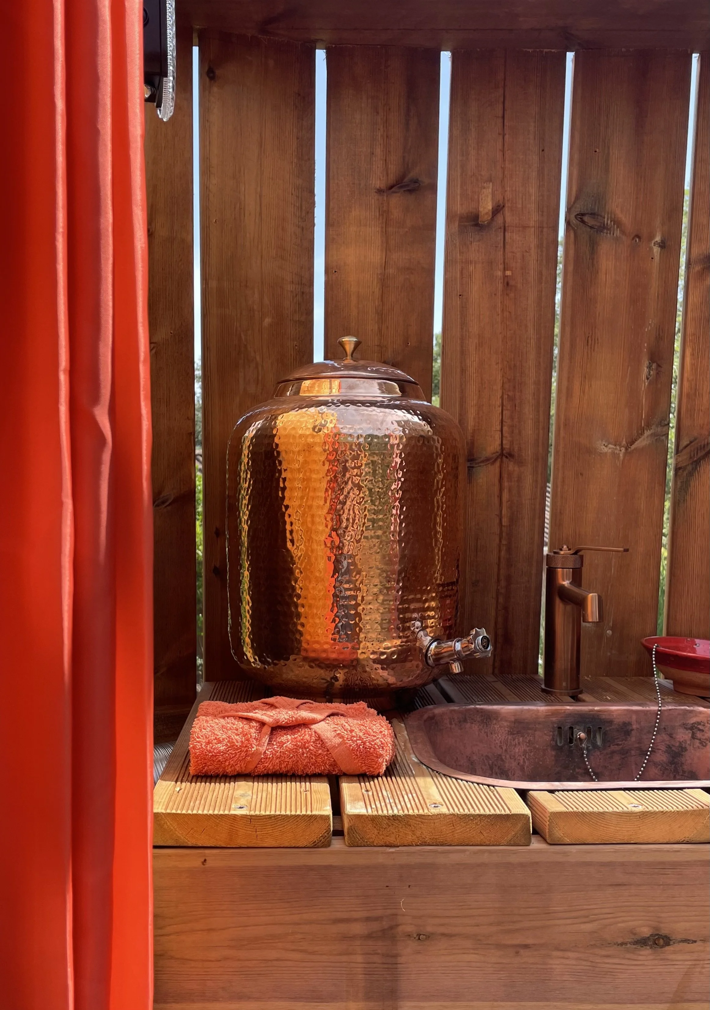 Bonbonne en cuivre utilisée pour la purification naturelle de l’eau, placée dans l’espace sanitaire et mise à disposition des hôtes pour une eau potable filtrée avec soin.