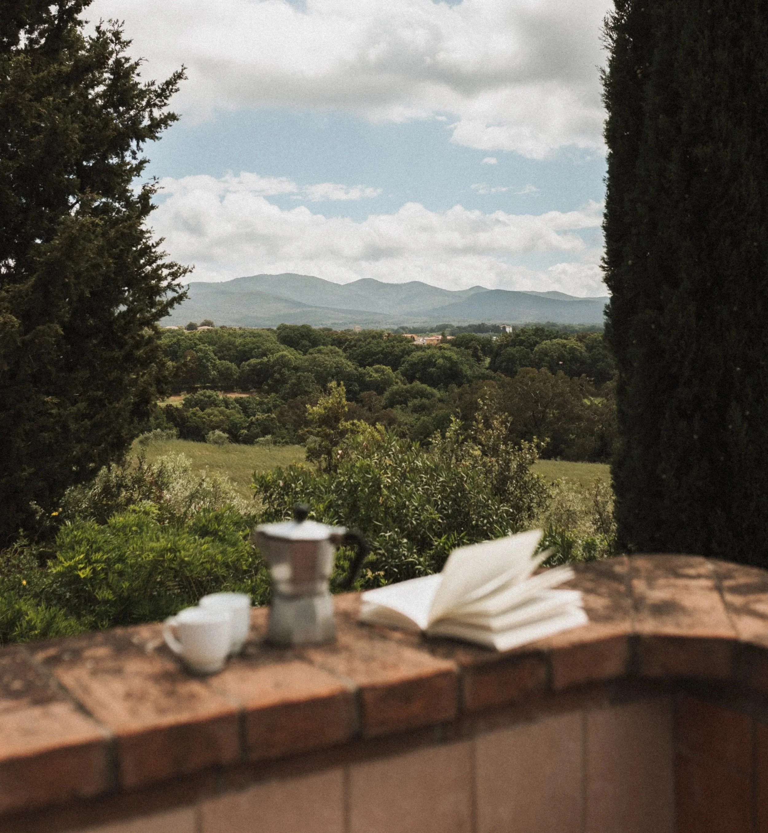 Espresso maker, two cups and a book on the balcony of our holiday apartment overlooking the Tuscan hills