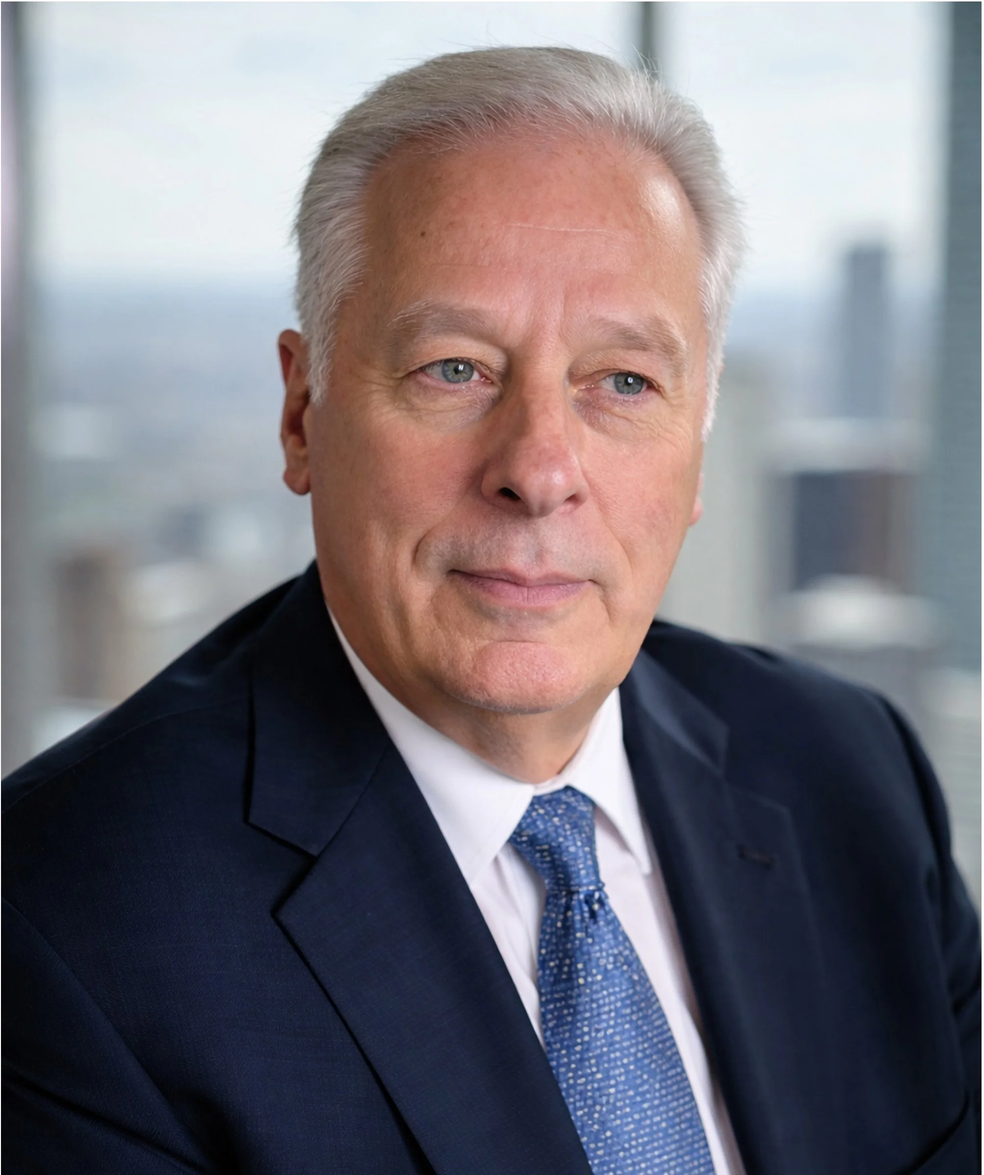 Portrait of a middle-aged man in a business suit with a city skyline in the background.