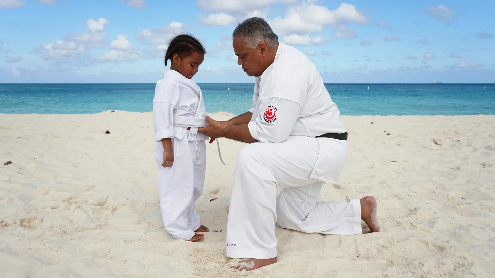 A man kneeling down next to a little girl on a beach photo