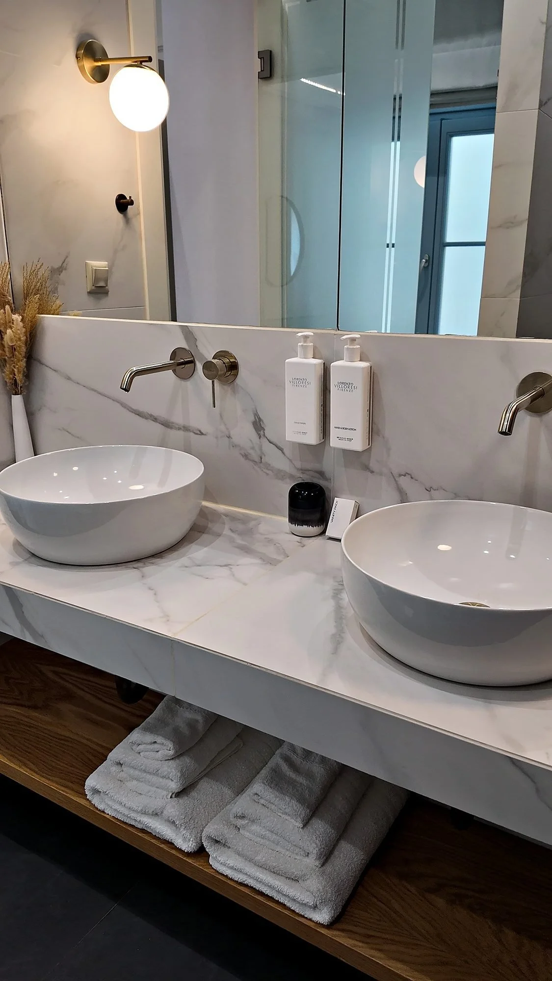 A marble double vanity with brass fittings and bath products in a suite bathroom at A77 Suites