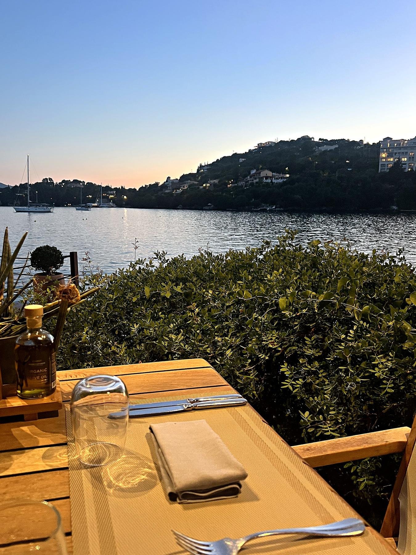 A table for one by the water at Yali, Grecotel Corfu Imperial, Corfu, just after sunset, with sailboats in the bay