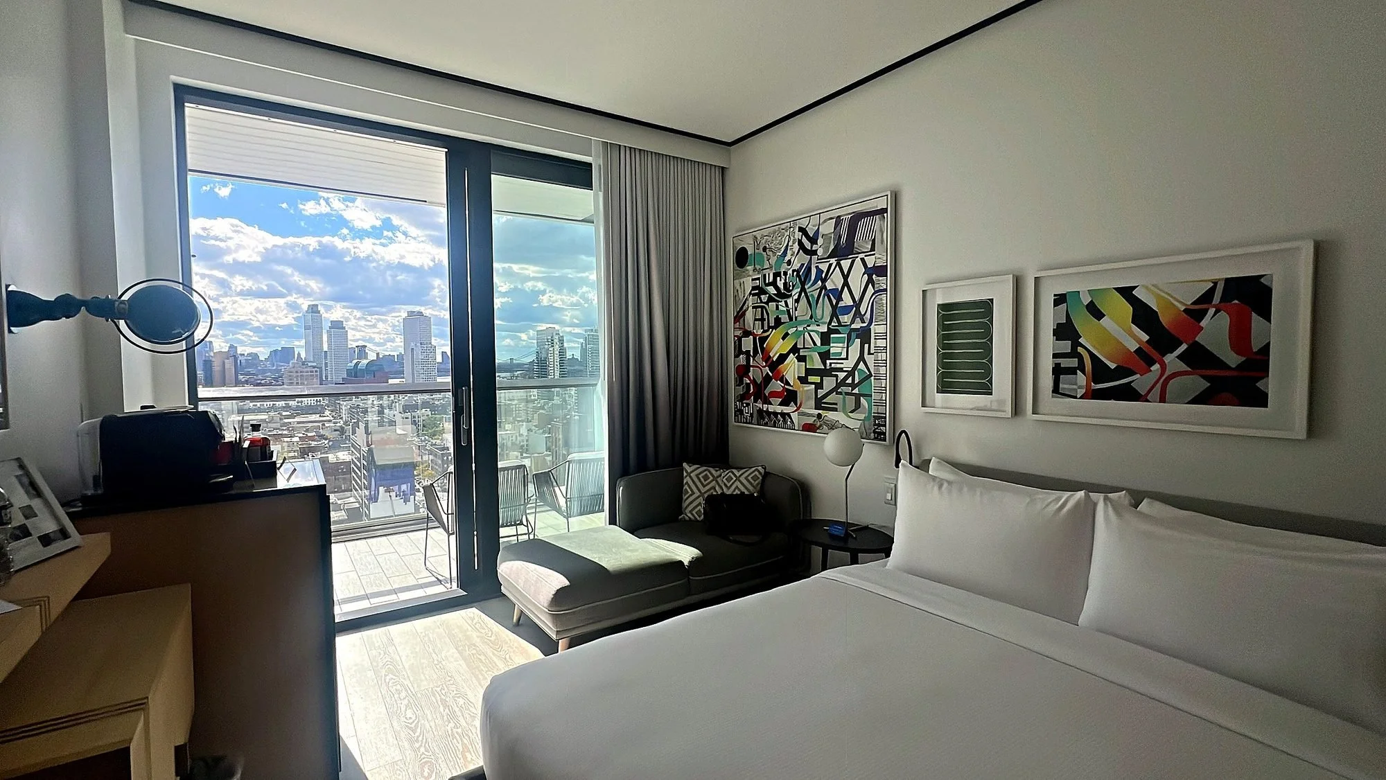 The King with Balcony room at The William Vale, a white bed facing the balcony door and a view of the city.