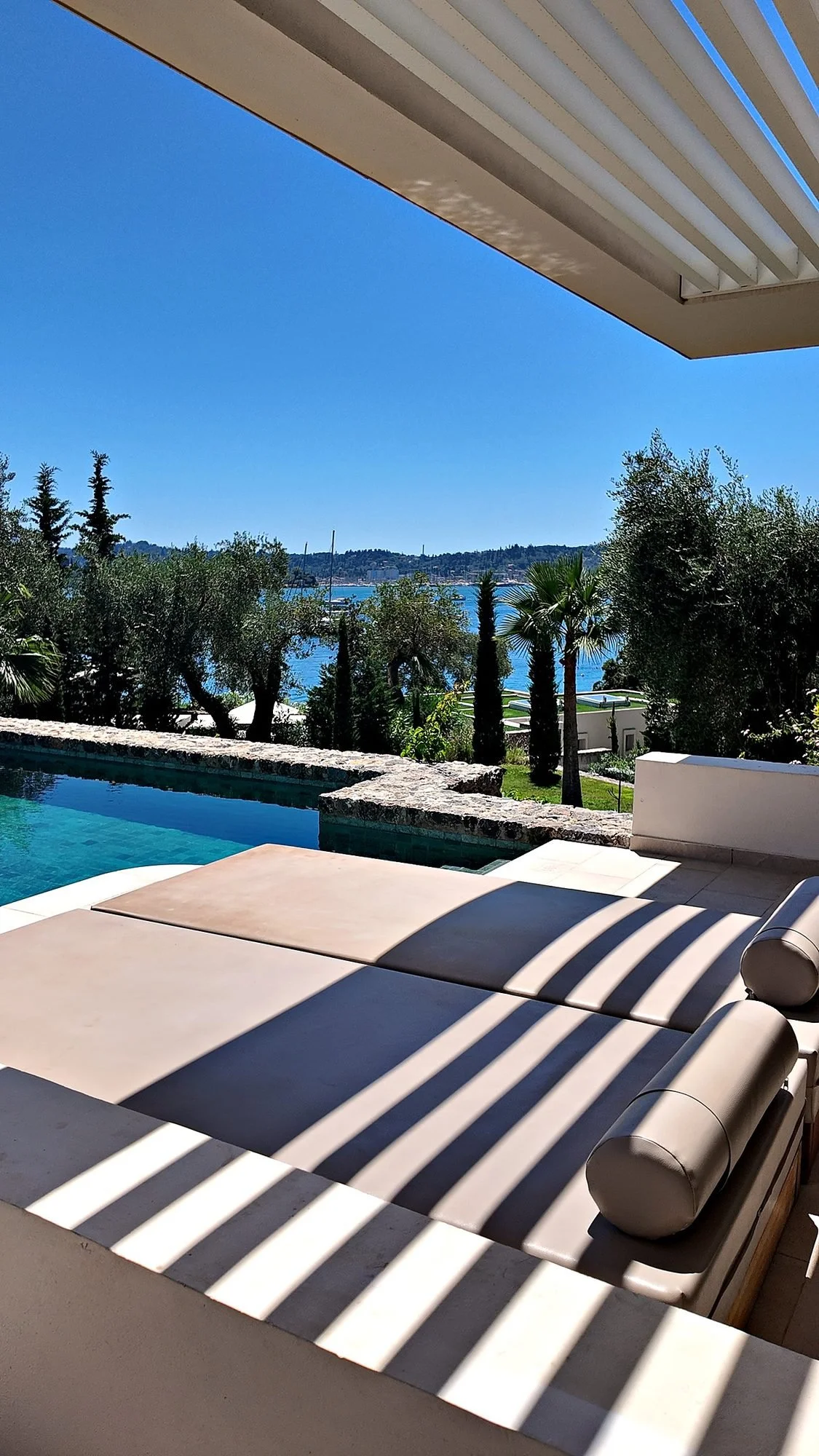 A Swim Up Junior Bungalow Suite at Grecotel Corfu Imperial, Corfu, from the bed through the glass doors to the private pool