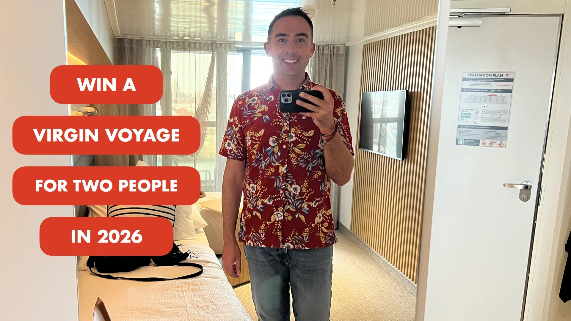 Fraser at Sea wearing a red floral shirt and jeans taking a mirror selfie in a hotel room, with a disposable bedding on the bed and a striped pillow among other items, with an evacuation plan on the door.