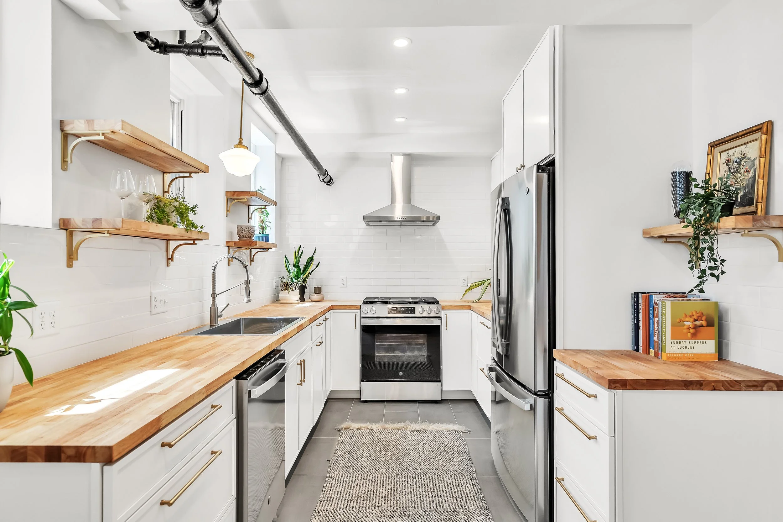 Replaced flooring, cabinets, lighting, and appliances. Opened up soffit to reveal steam pipe. Reclaimed shelving. Reconfigured layout to maximize storage & natural light.
