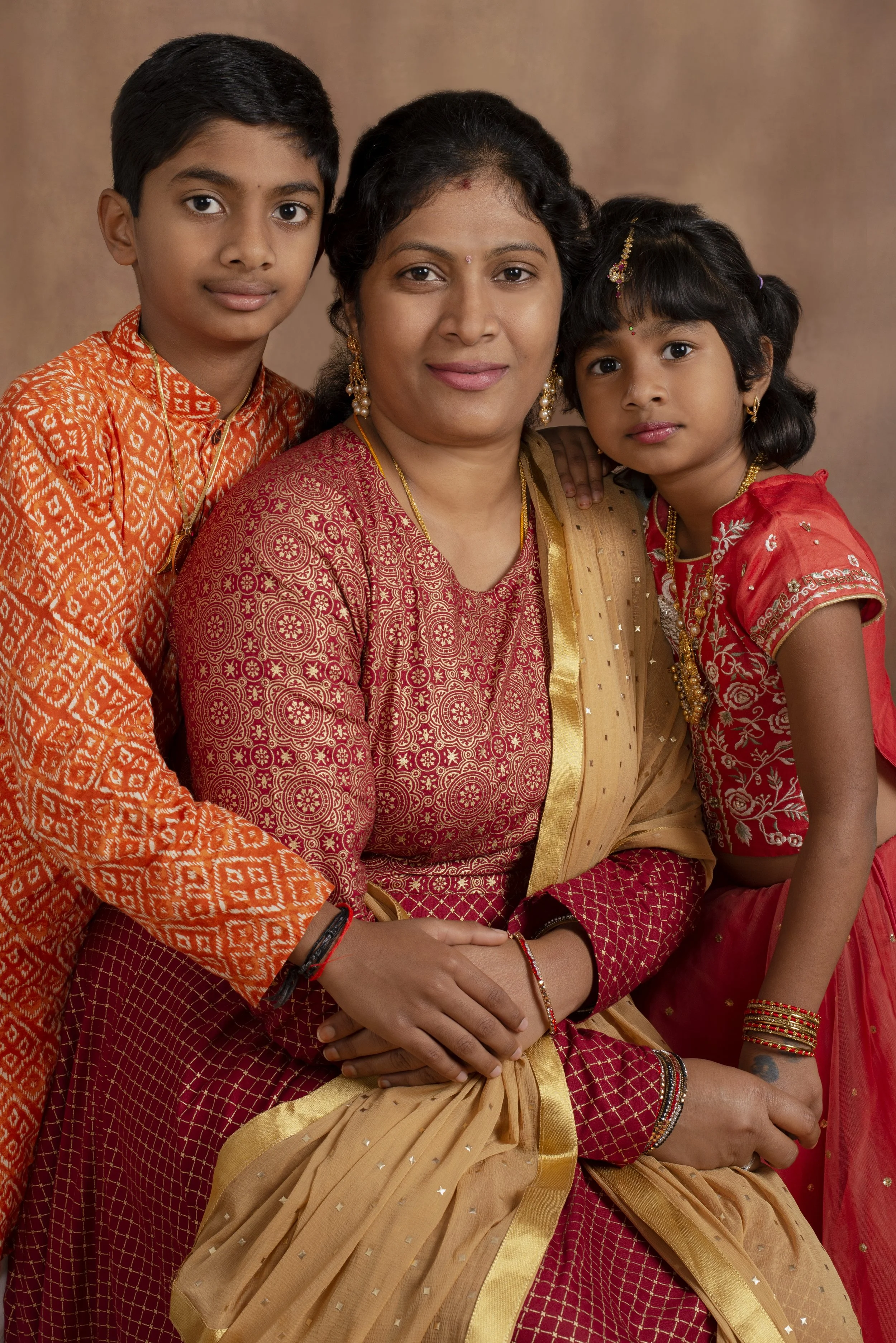 Indian mother and two children dressed in colorful traditional attire, posing for a portrait
