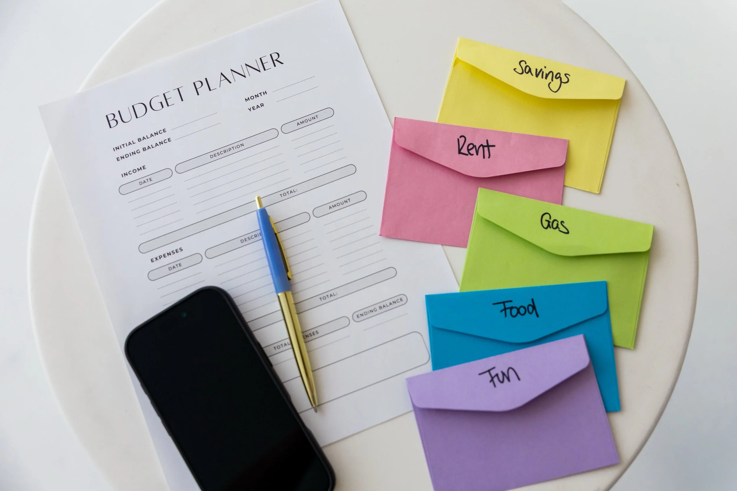 Image of a budget planner plus envelopes for savings, rent, gas, food and fun