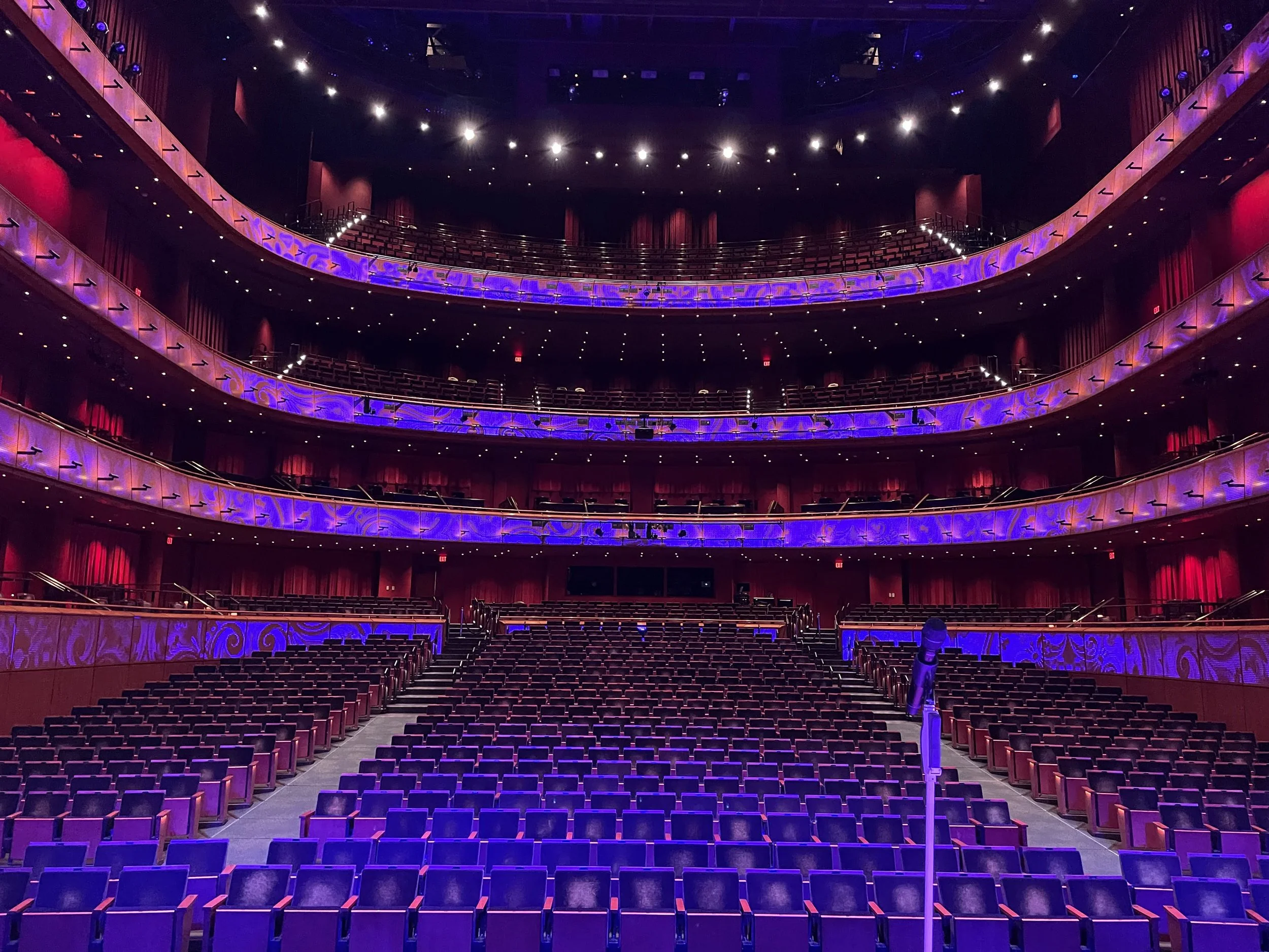 A photo from the actors viewpoint on stage looking out into the audience with a blue hue during Hasan Minhaj Load in.