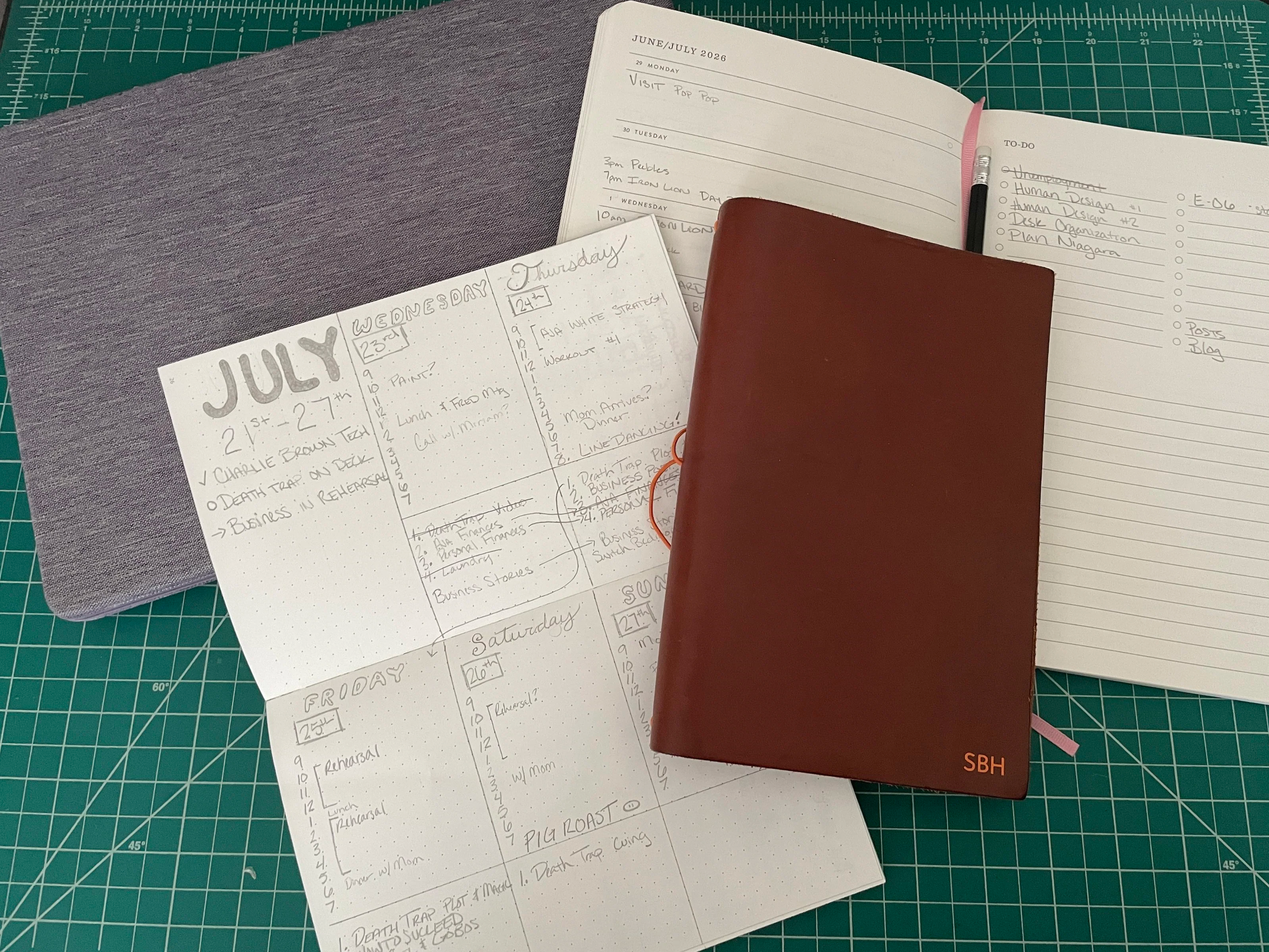 Photo of a bullet journal planner, notebook cover initialed SBH and a planner in the background