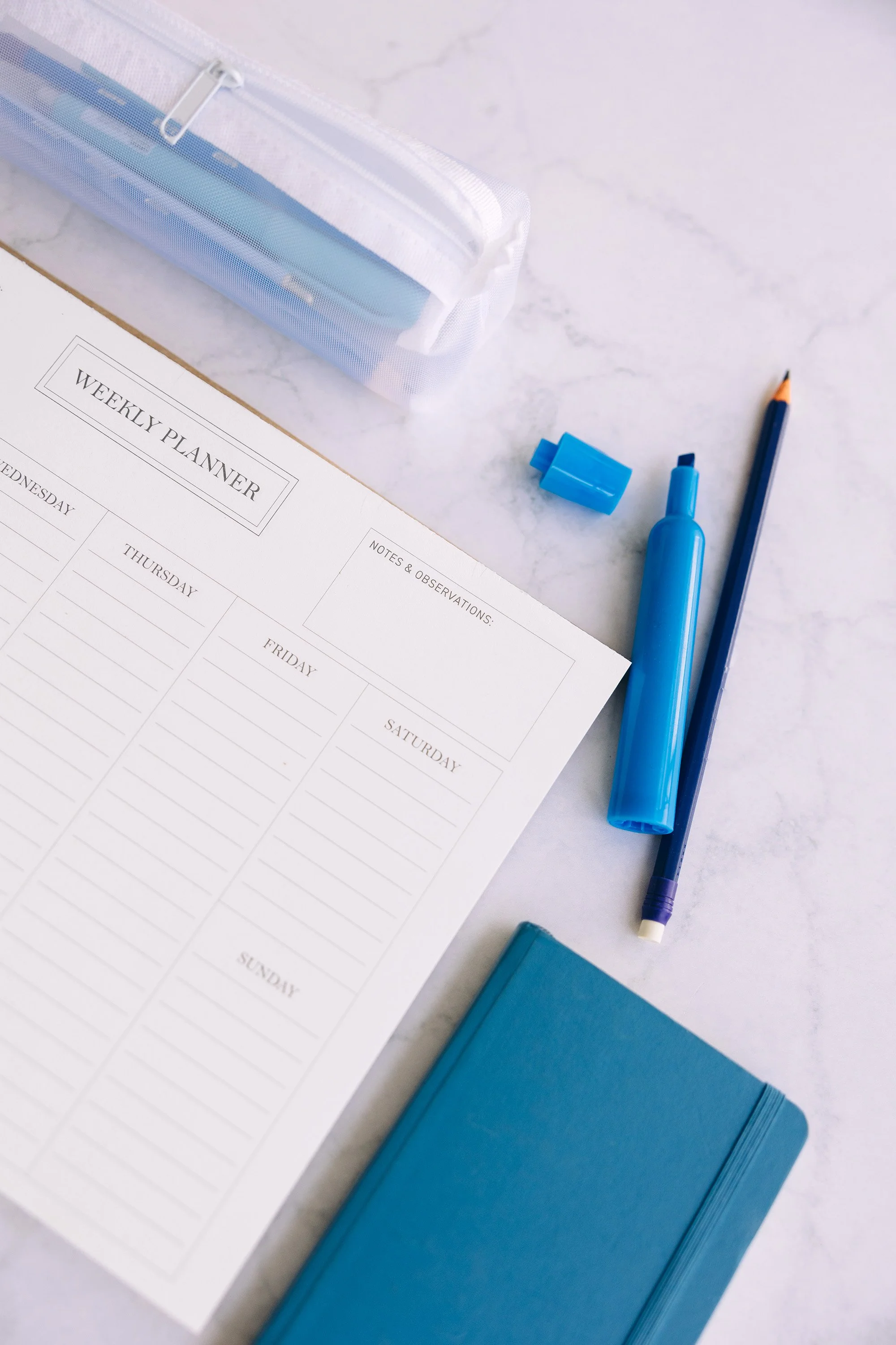 Image of a weekly planner with blue notebook, highlighter and pencil