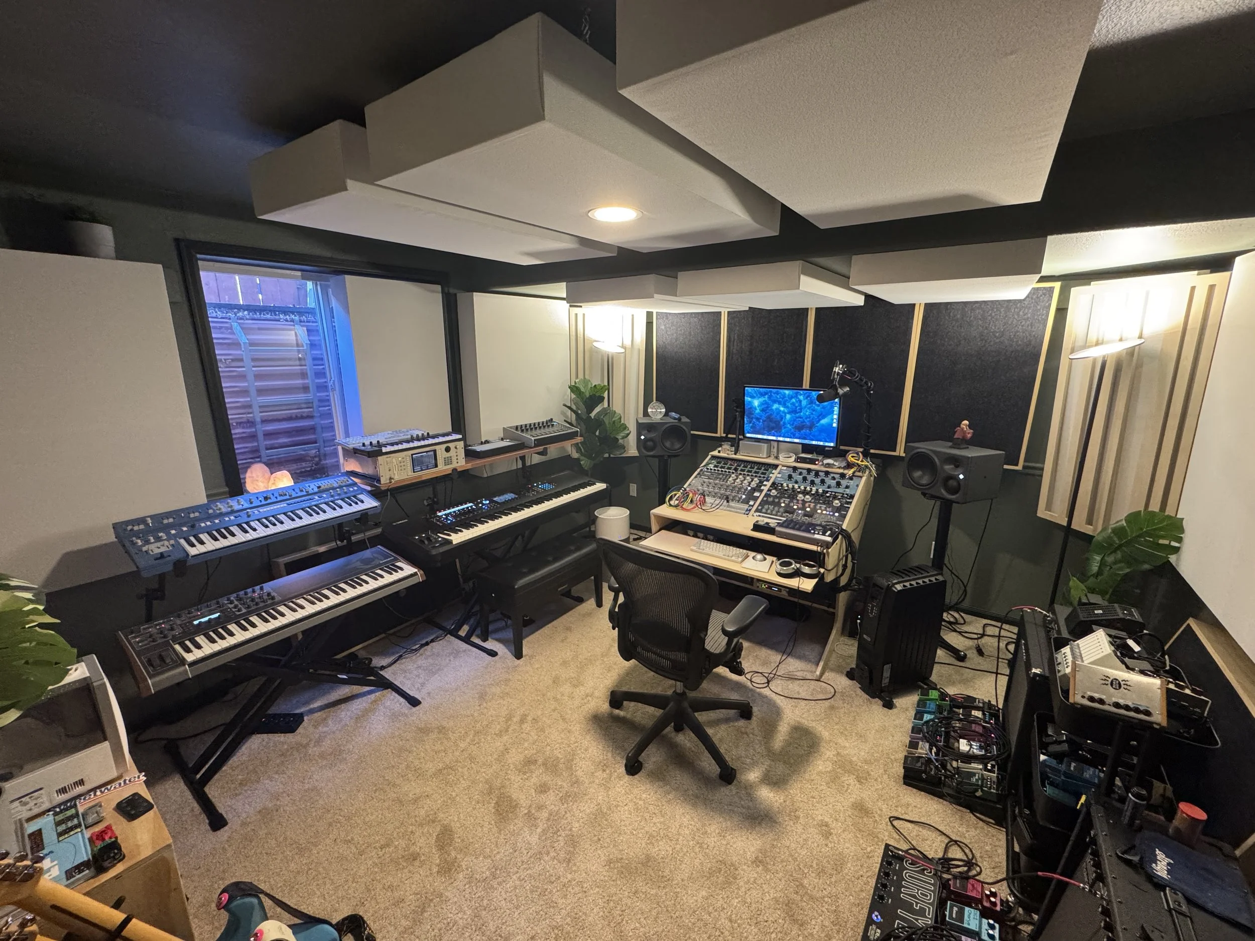 A wide shot in The Cat Mansion, showing extensive sound treatment, Neumann monitors, synthesizers, guitars, and other musical equipment.