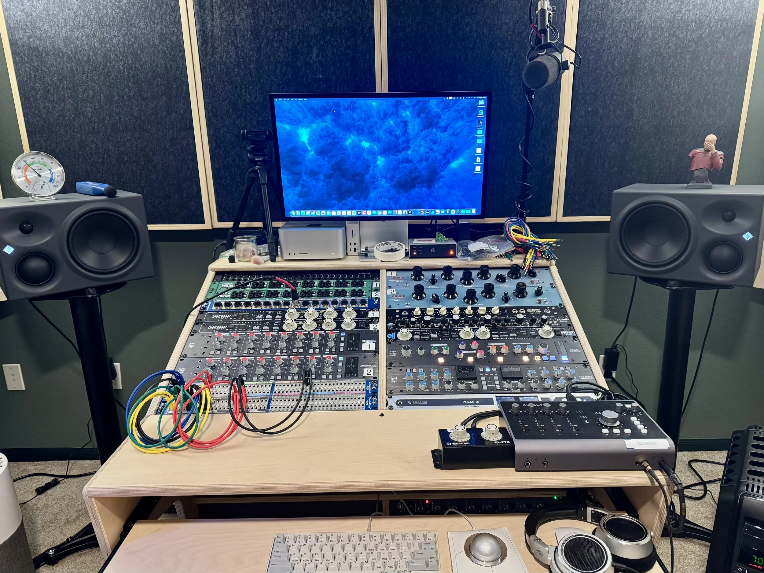 A music production desk featuring rack units like SSL Compressors, SSL Preamps, Empirical Distressors, EQs, and other audio equipment at The Cat Mansion.