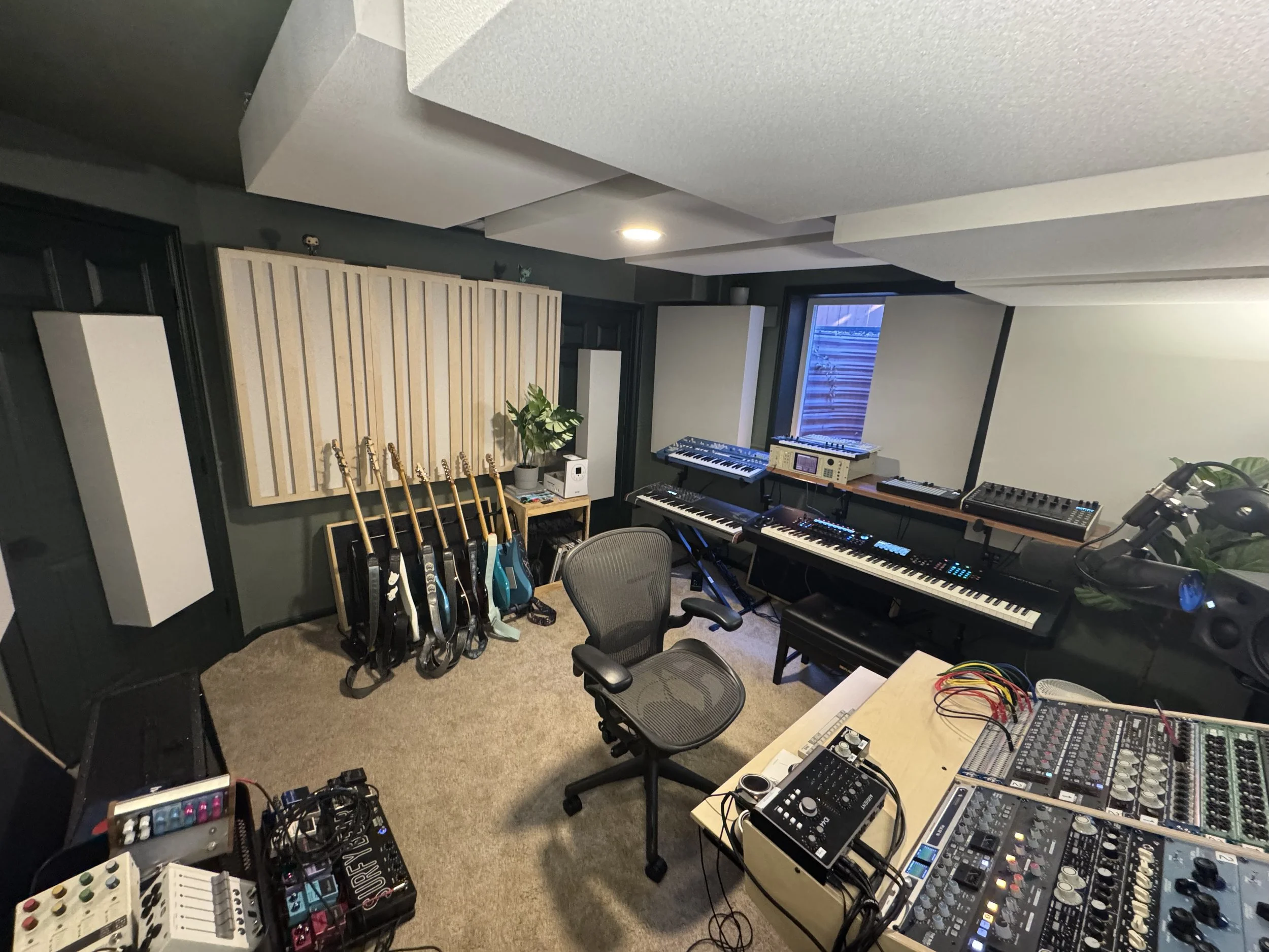 Music recording, production, mixing, and mastering space with guitars, outboard analog gear, synthesizers, and effects.