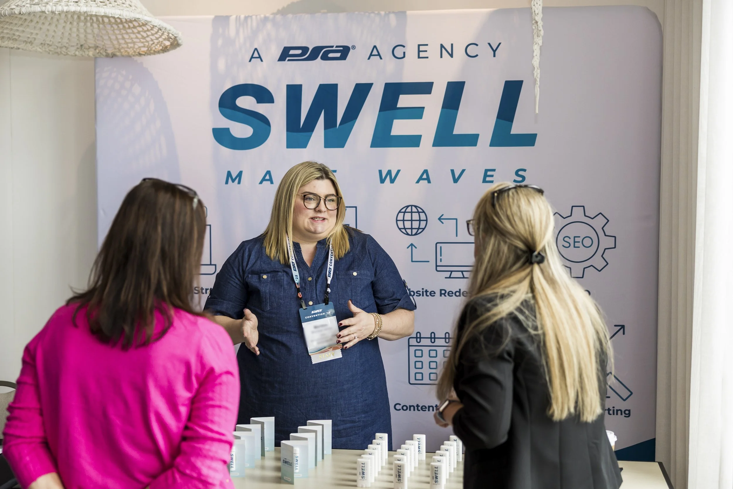 Event sponsor speaks to booth visitors during a convention.