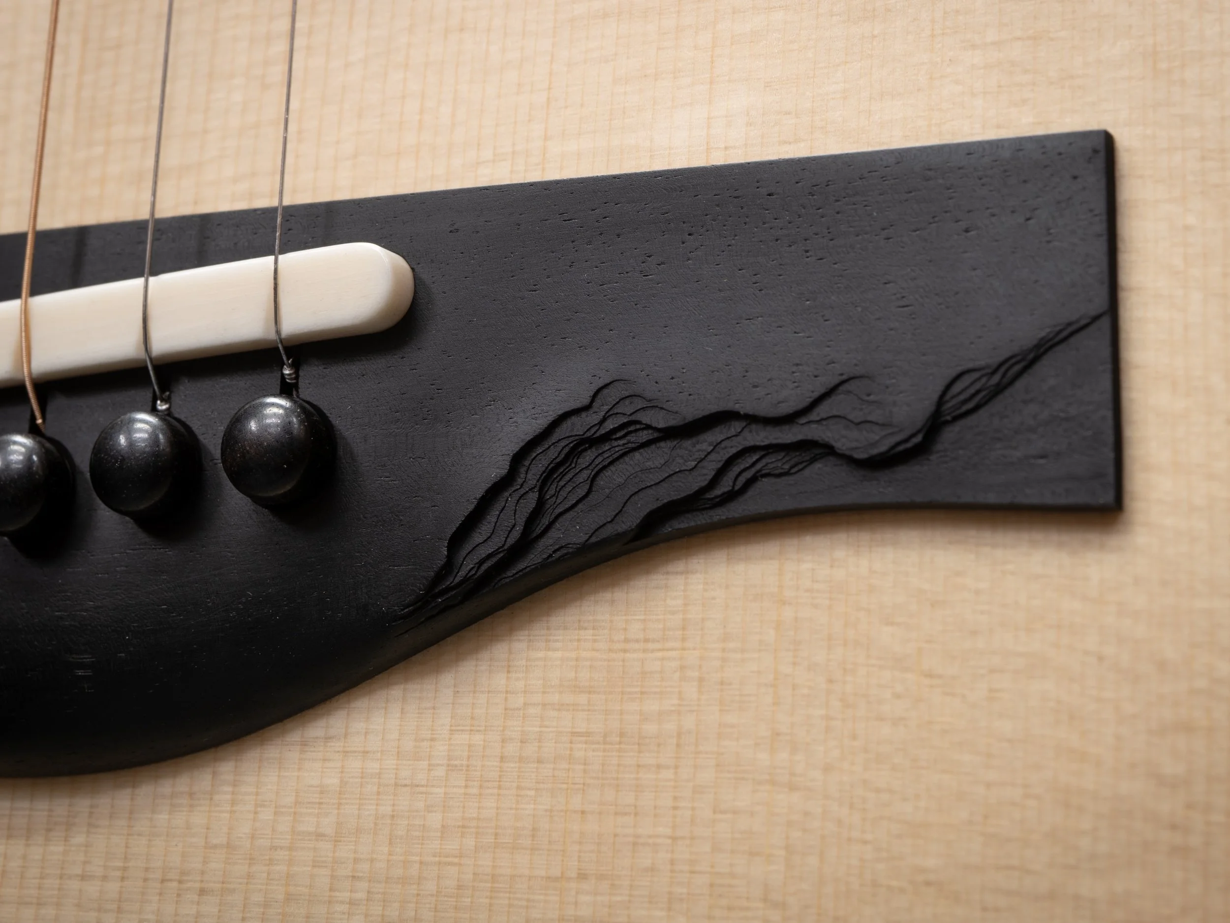 Natural live edge texture on ebony guitar bridge.