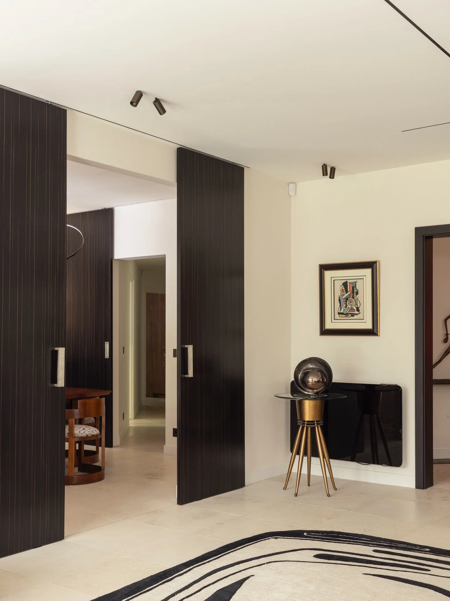 Dans le projet Neuilly, chaque &eacute;l&eacute;ment a &eacute;t&eacute; pens&eacute; pour structurer et sublimer l&rsquo;espace. Ici, les portes toute hauteur en bois sombre cr&eacute;ent un rythme fort d&egrave;s l&rsquo;entr&eacute;e. Leur finitio