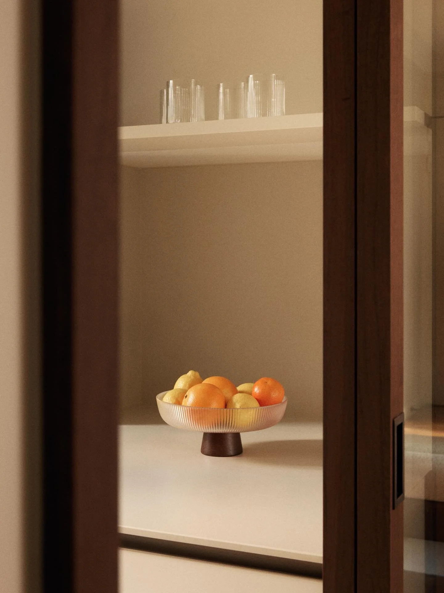 Vue sur la cuisine du projet Bourdonnais.
Une ambiance douce et minimaliste pens&eacute;e par @maison_e2ms : fa&ccedil;ades mates, plan de travail clair, robinetterie cuivr&eacute;e, et portes vitr&eacute;es encadr&eacute;es de bois fonc&eacute; pour