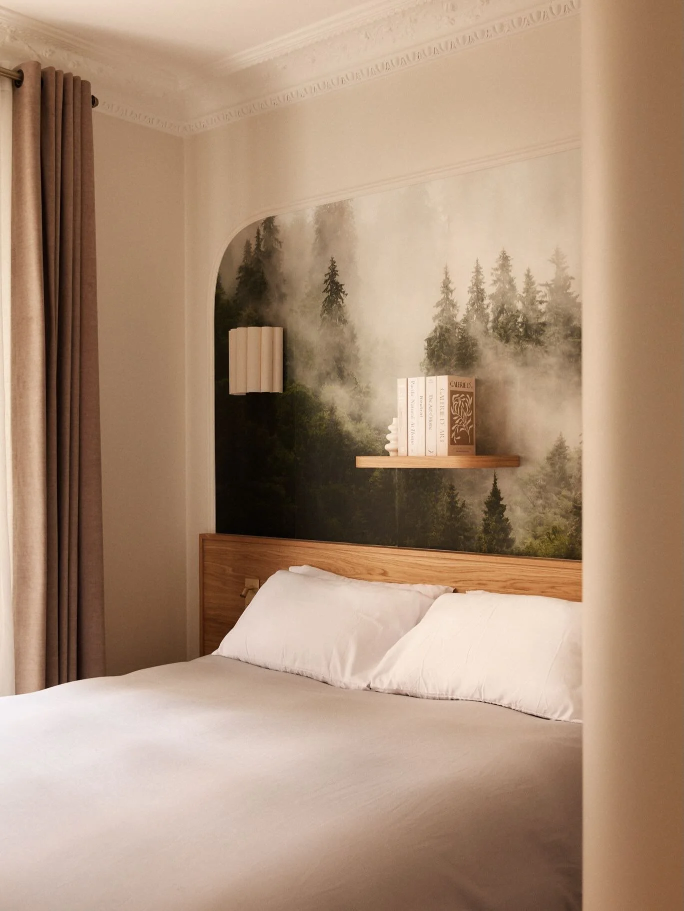 Dans cette chambre du projet Bourdonnais, le papier peint panoramique occupe tout le mur de t&ecirc;te de lit et donne le ton de la pi&egrave;ce. Peintures, menuiseries en ch&ecirc;ne, &eacute;tag&egrave;re flottante sur-mesure : l&rsquo;ensemble a &