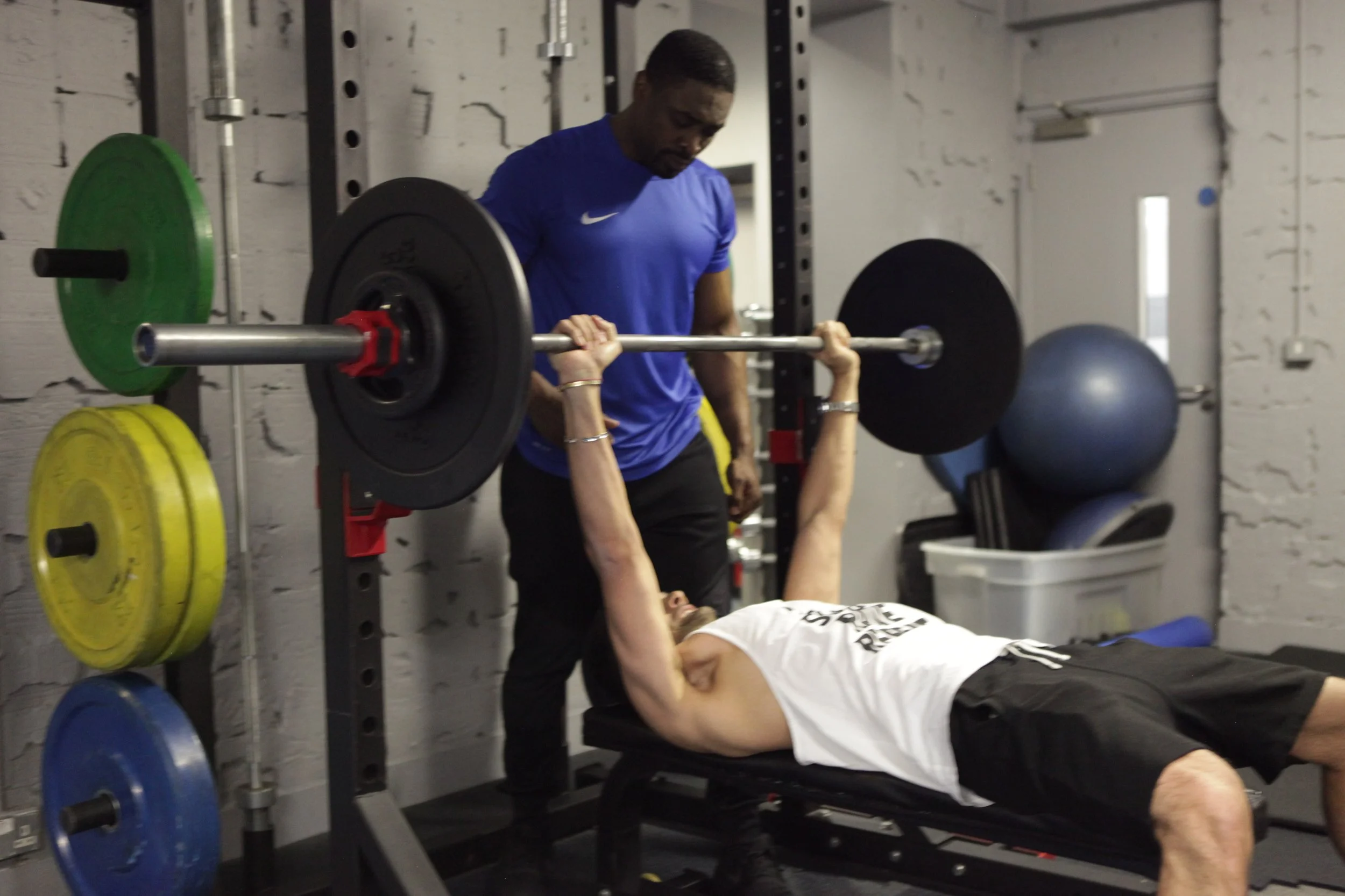 Personal trainer Otaniyien Ekiomado coaching a client doing a bench press.