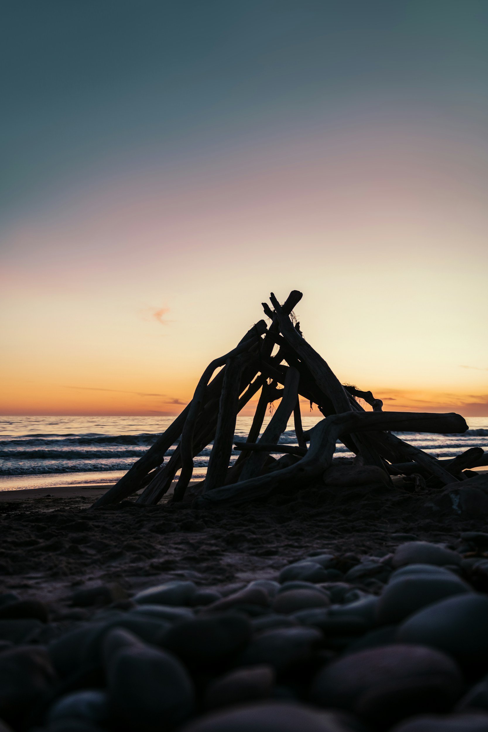 Ventura beach at sunset with hut made from driftwood on shore