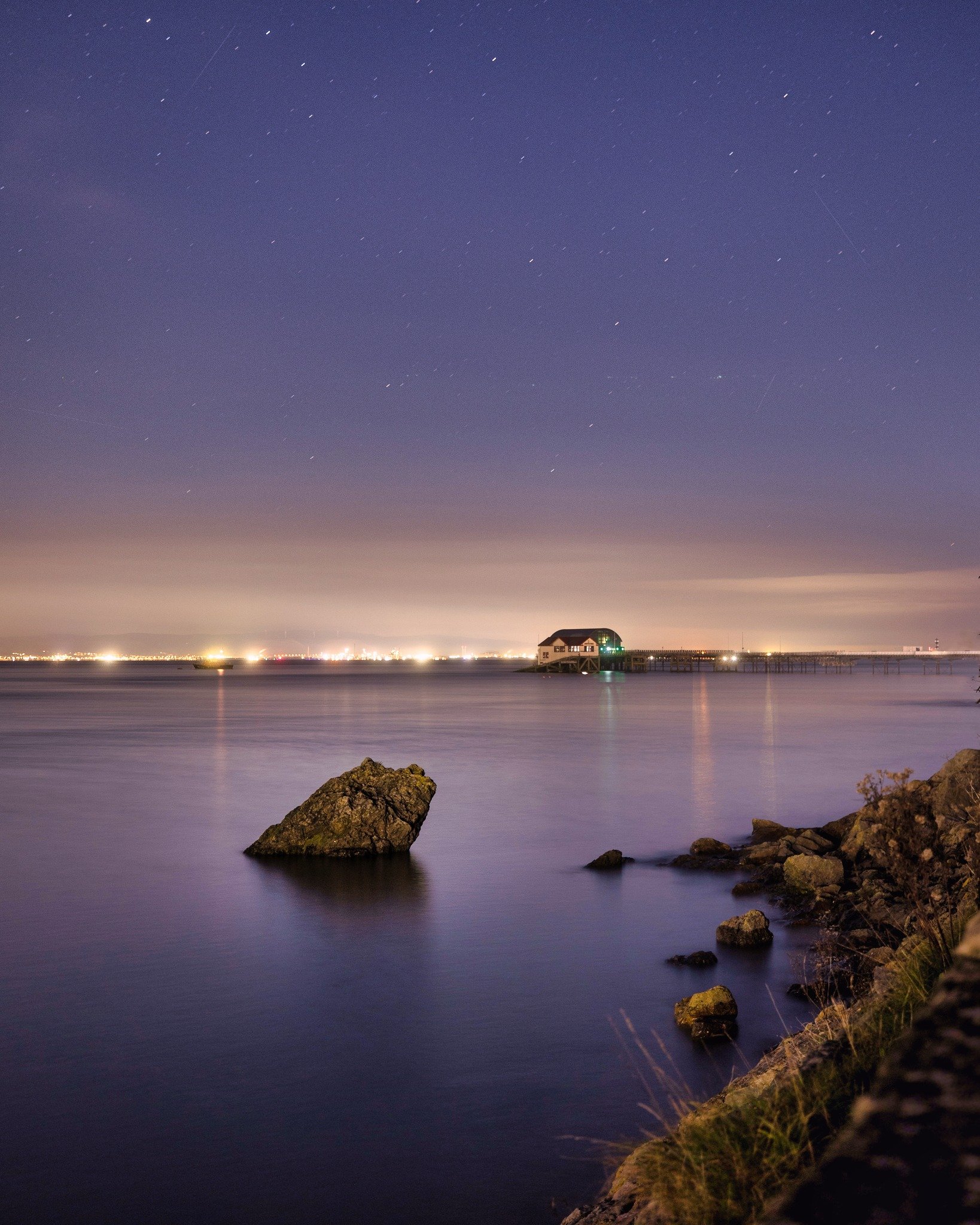 Nighttime coastal scene with rocks and building