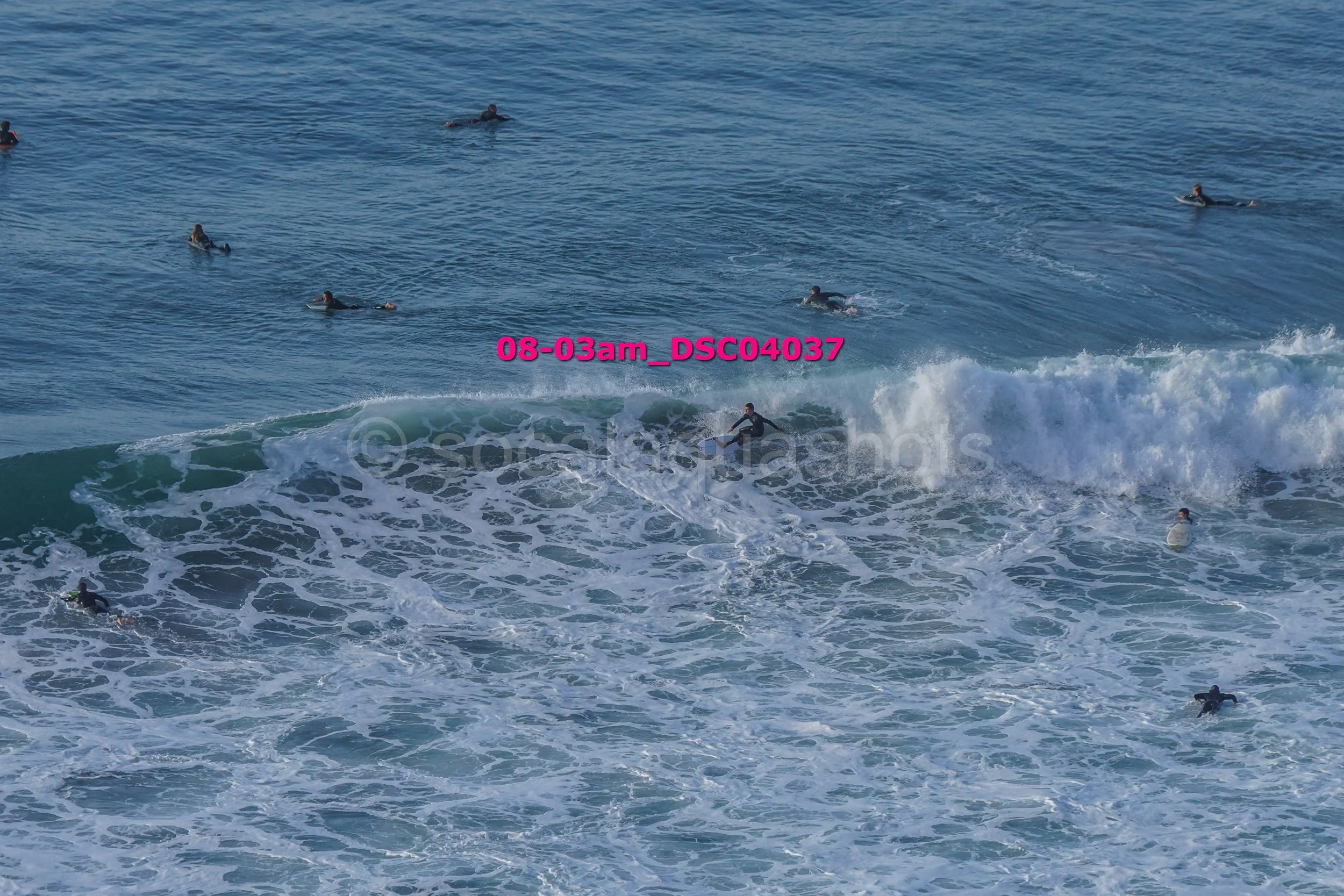 A group of people surfing and swimming in the ocean with waves.