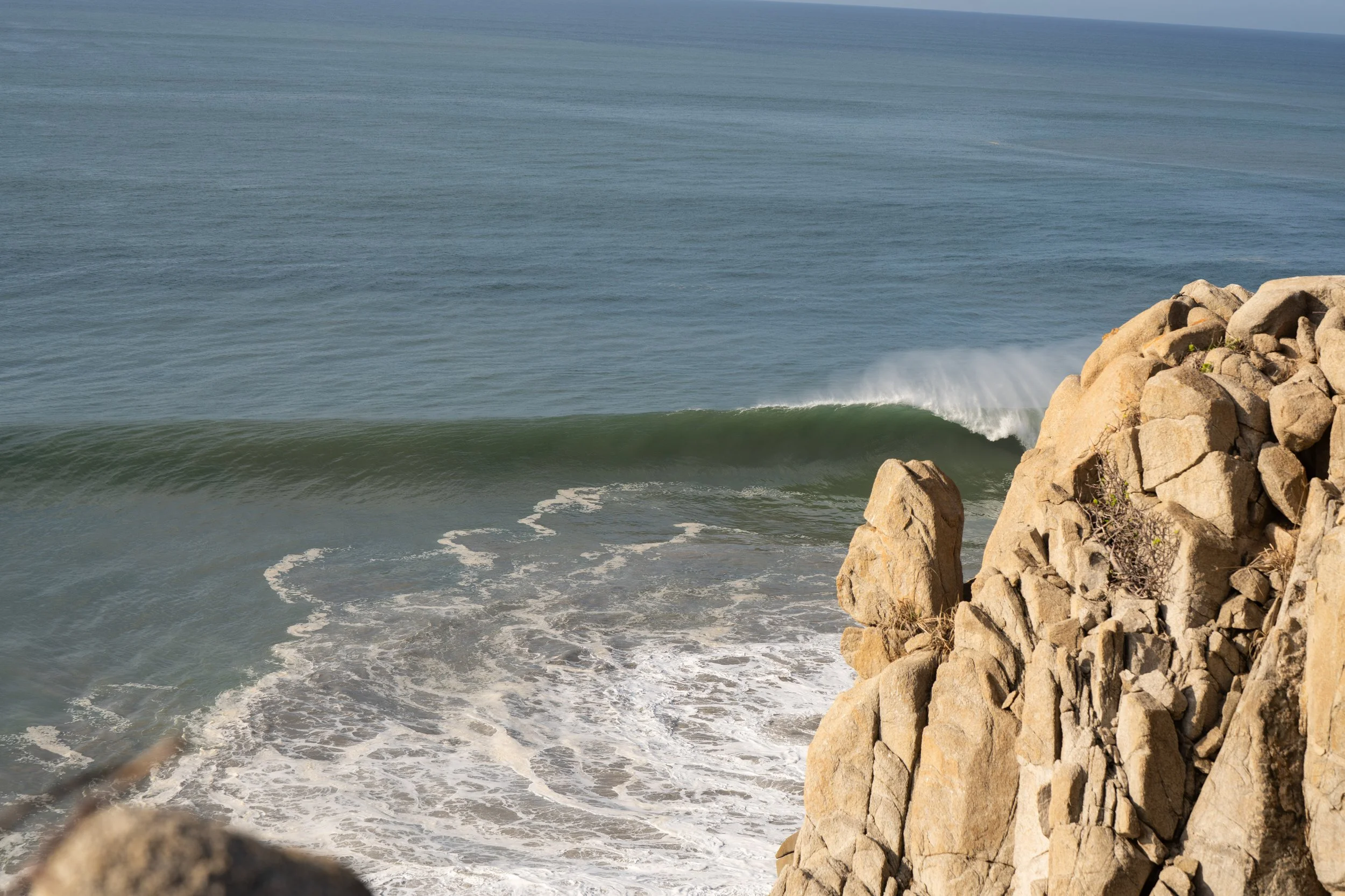View of the ocean with waves crashing against rocks on the shoreline.