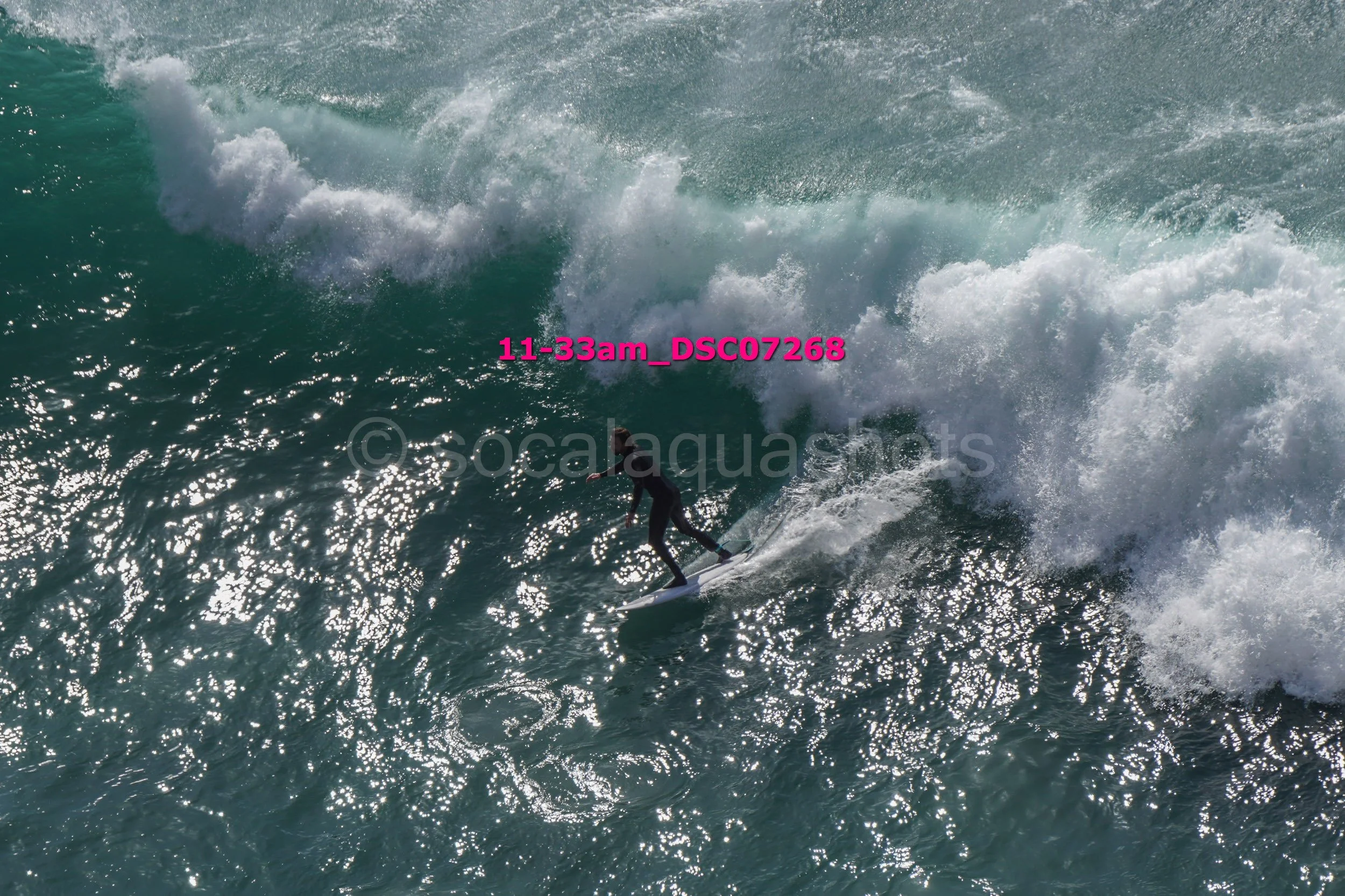 A person surfing on a large wave in the ocean during daylight.