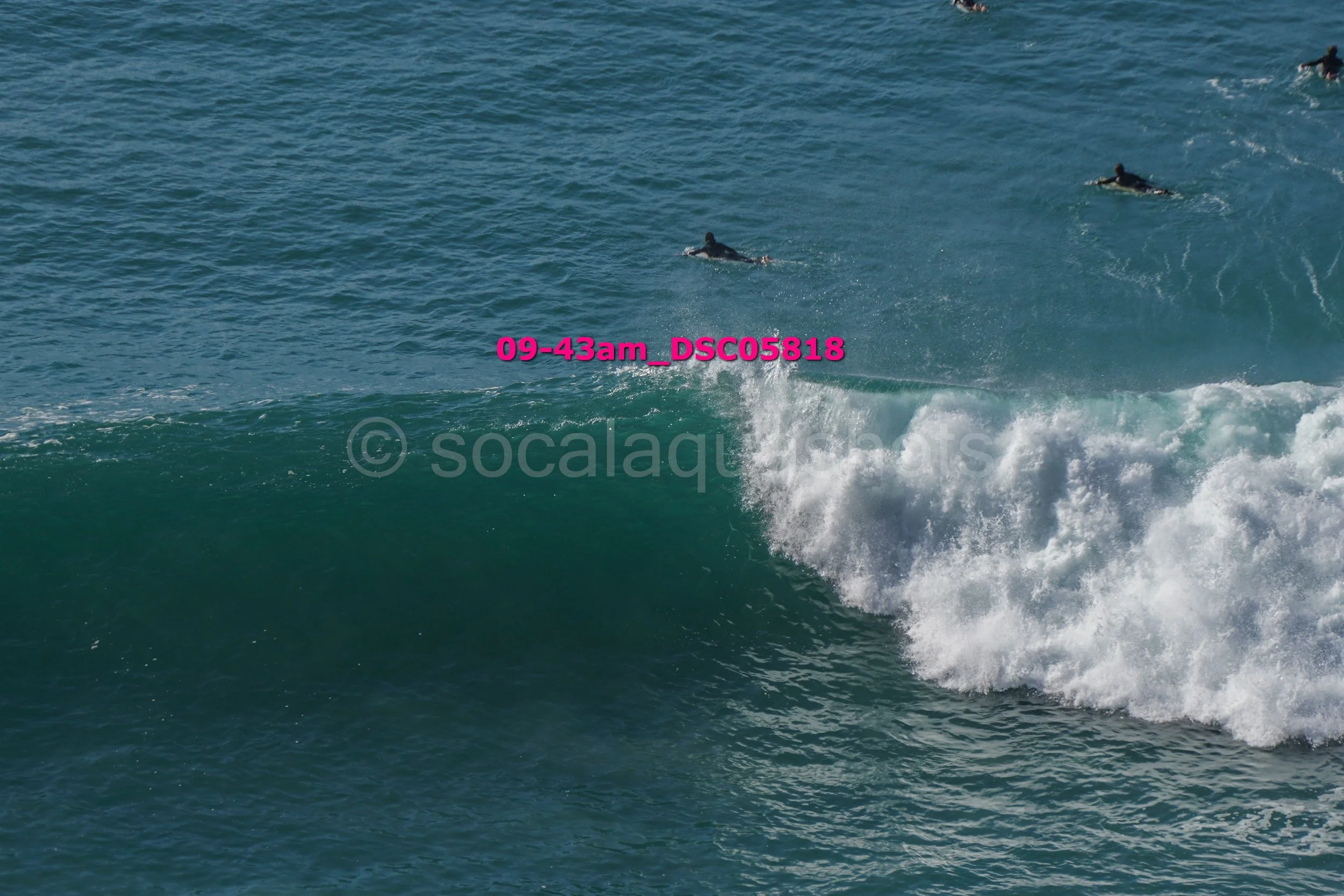 View of ocean waves with surfers in the water, some catching waves.