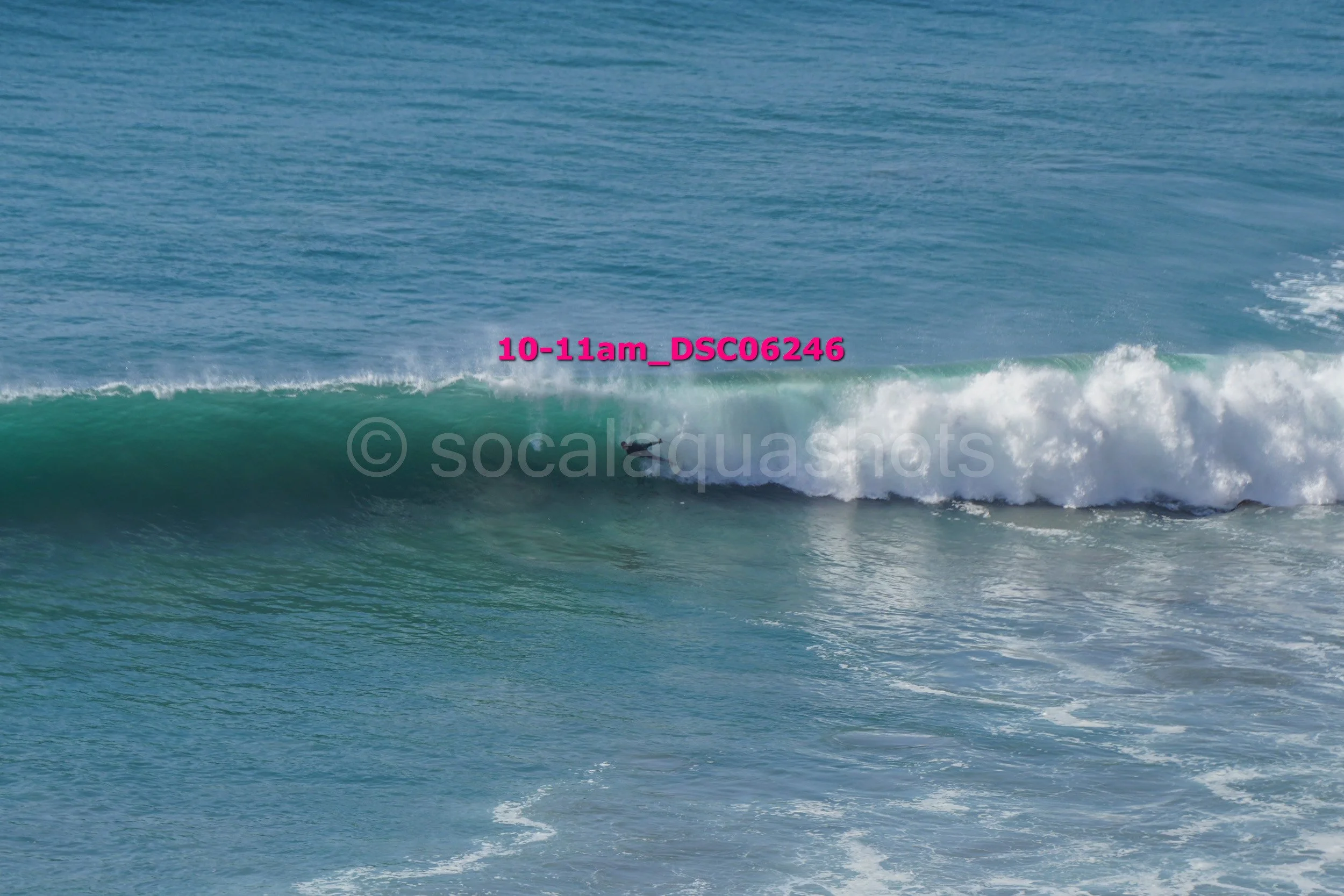 Wave breaking in the ocean with a surfer riding inside the wave.