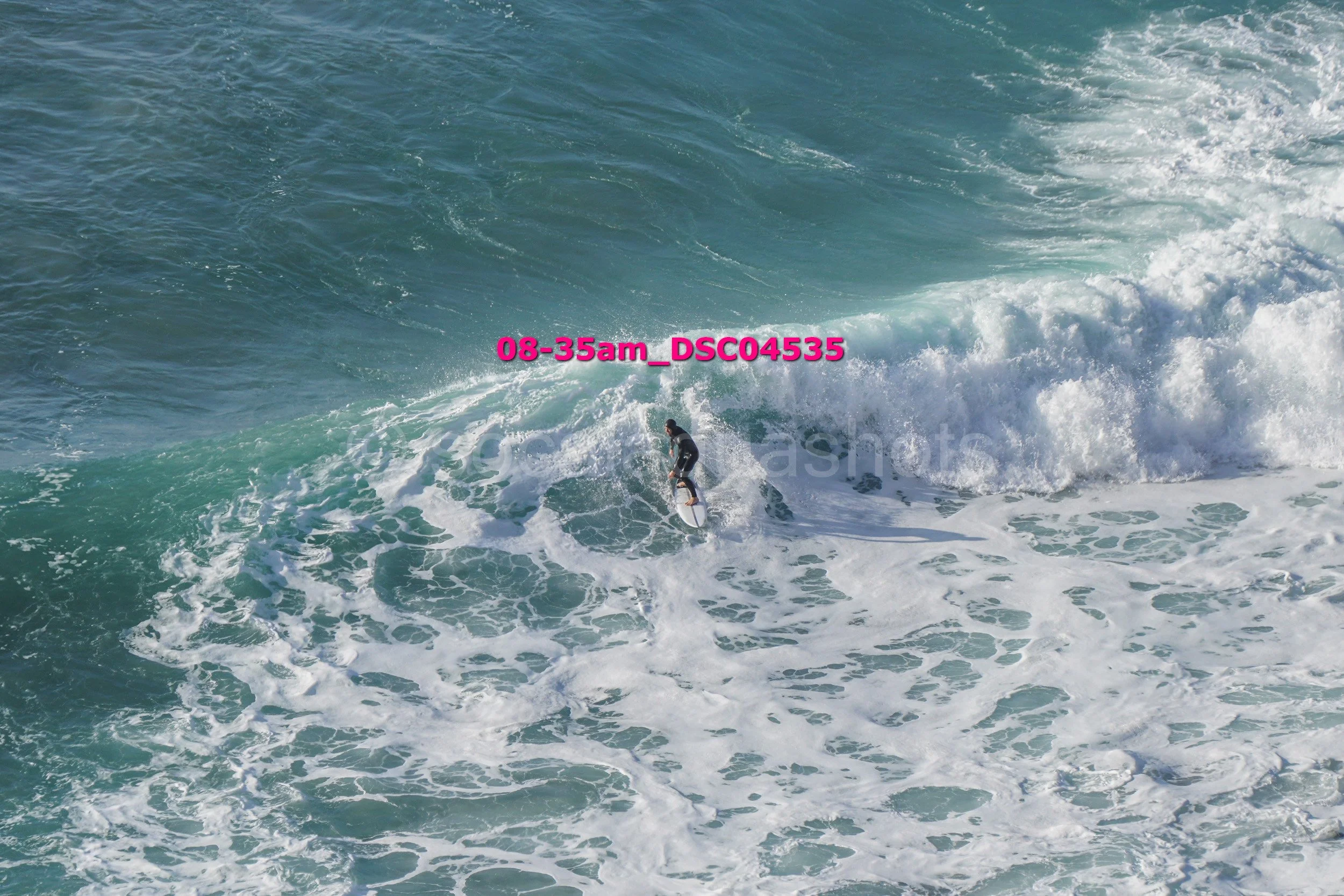 A person surfing on a large wave in the ocean.