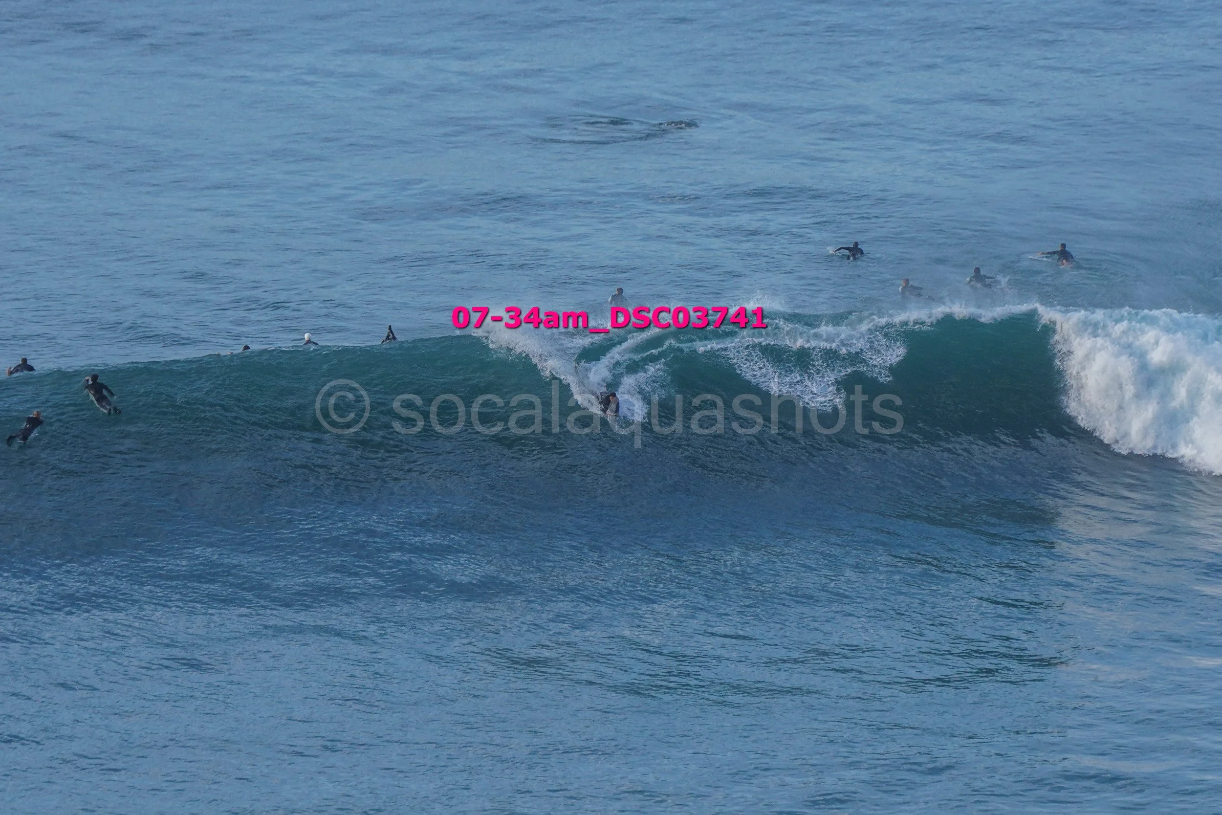 People surfing on ocean waves with some starting to ride the wave while others are waiting in the water