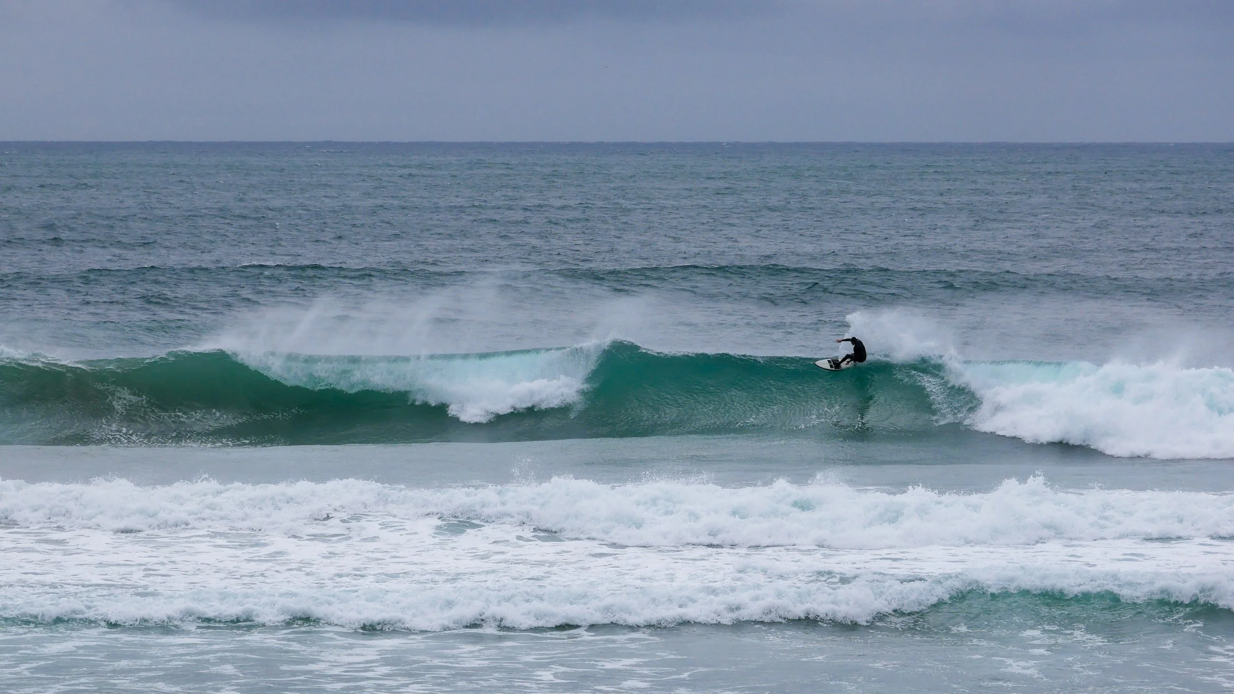 Surfer riding a wave in the ocean on a cloudy day