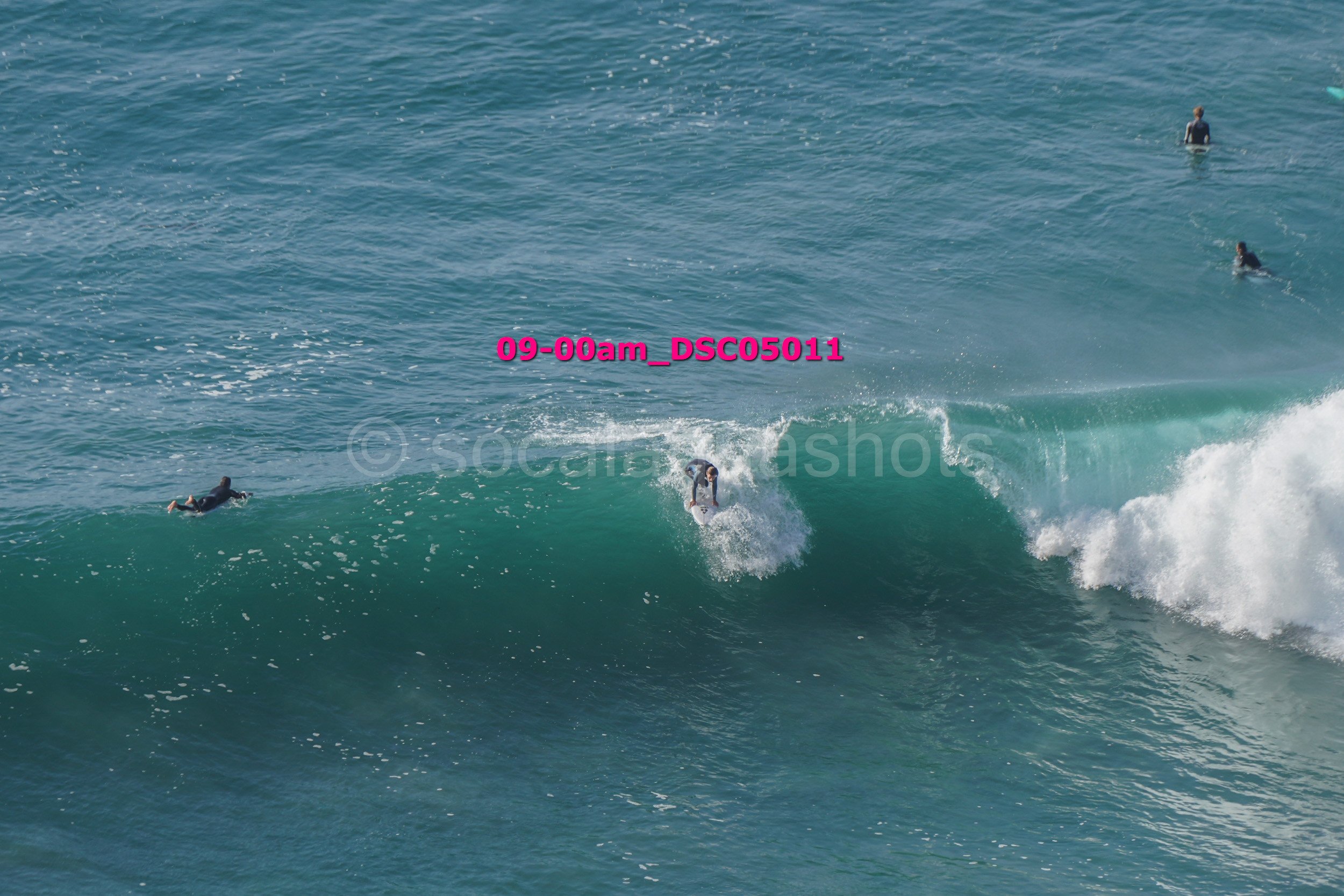 A surfer riding a wave with surfers in the water in the background.