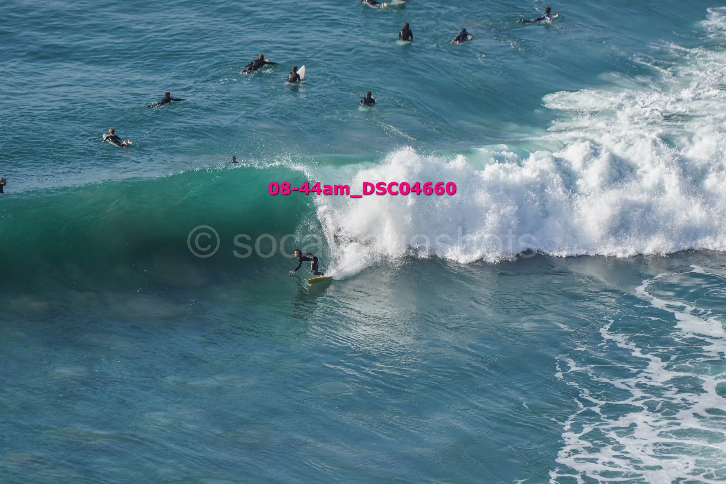 Surfer riding a wave with multiple surfers in the water in the background.