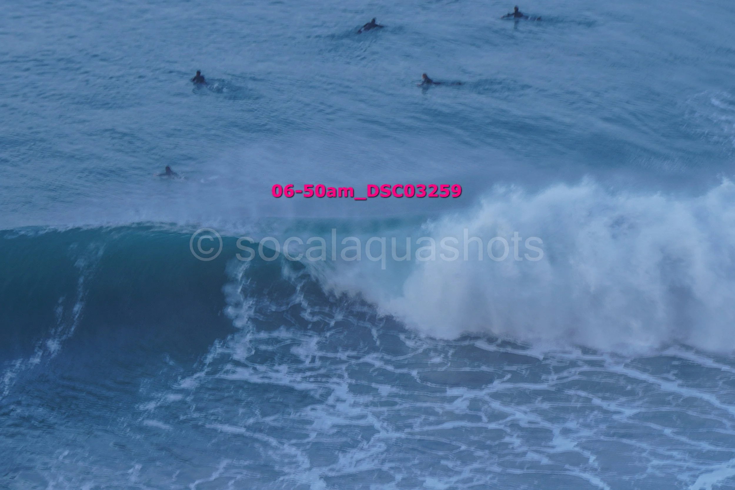 Multiple surfers on a large wave in the ocean during sunrise or sunset, with a caption overlay in pink text reading '06-50am_DSC03259'.