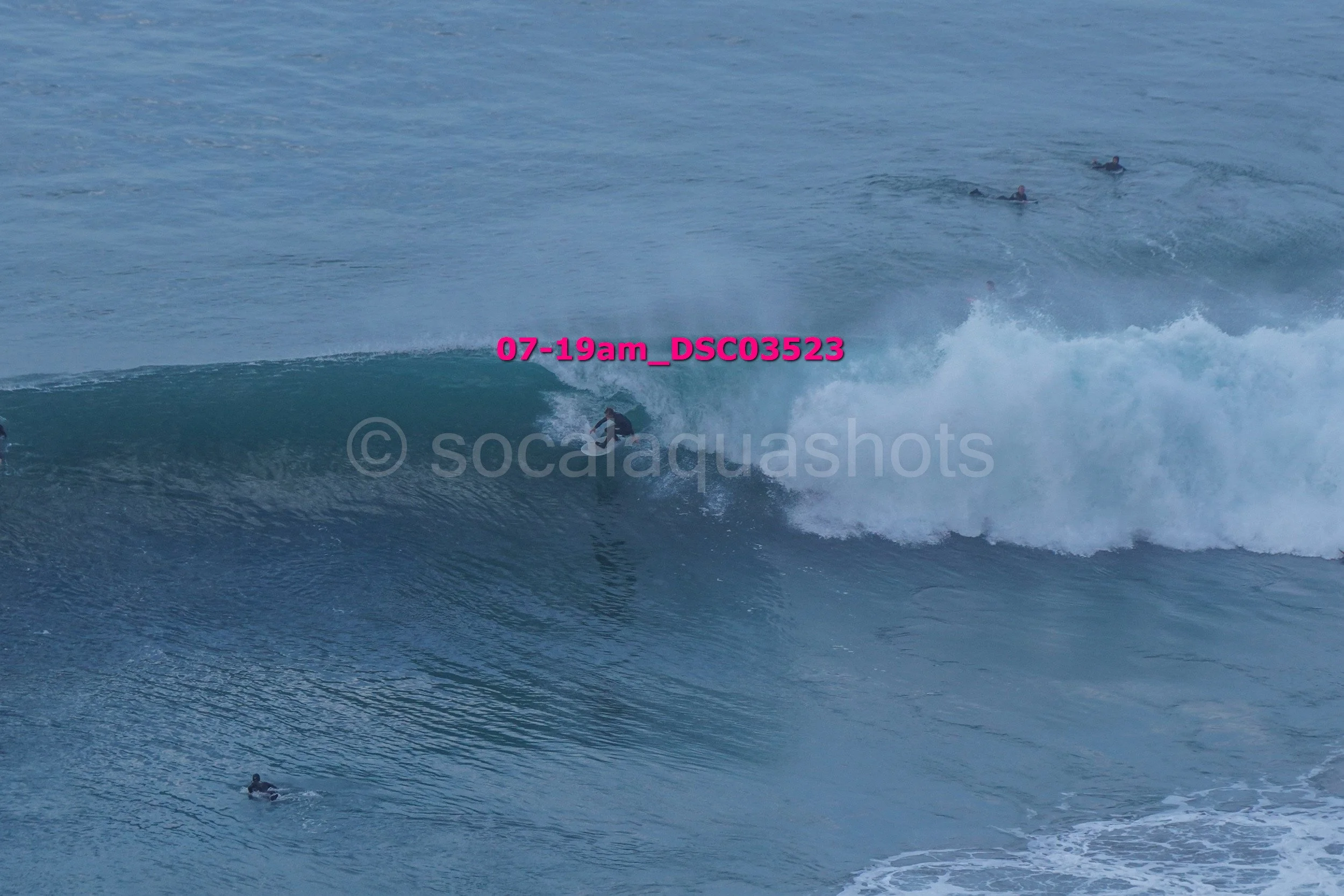 A person surfing a wave in the ocean with other surfers in the background.
