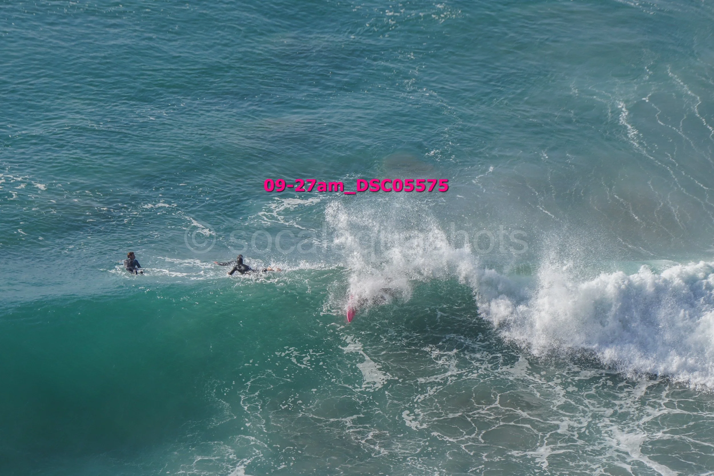 Surfers falling off a surfboard in large ocean waves.