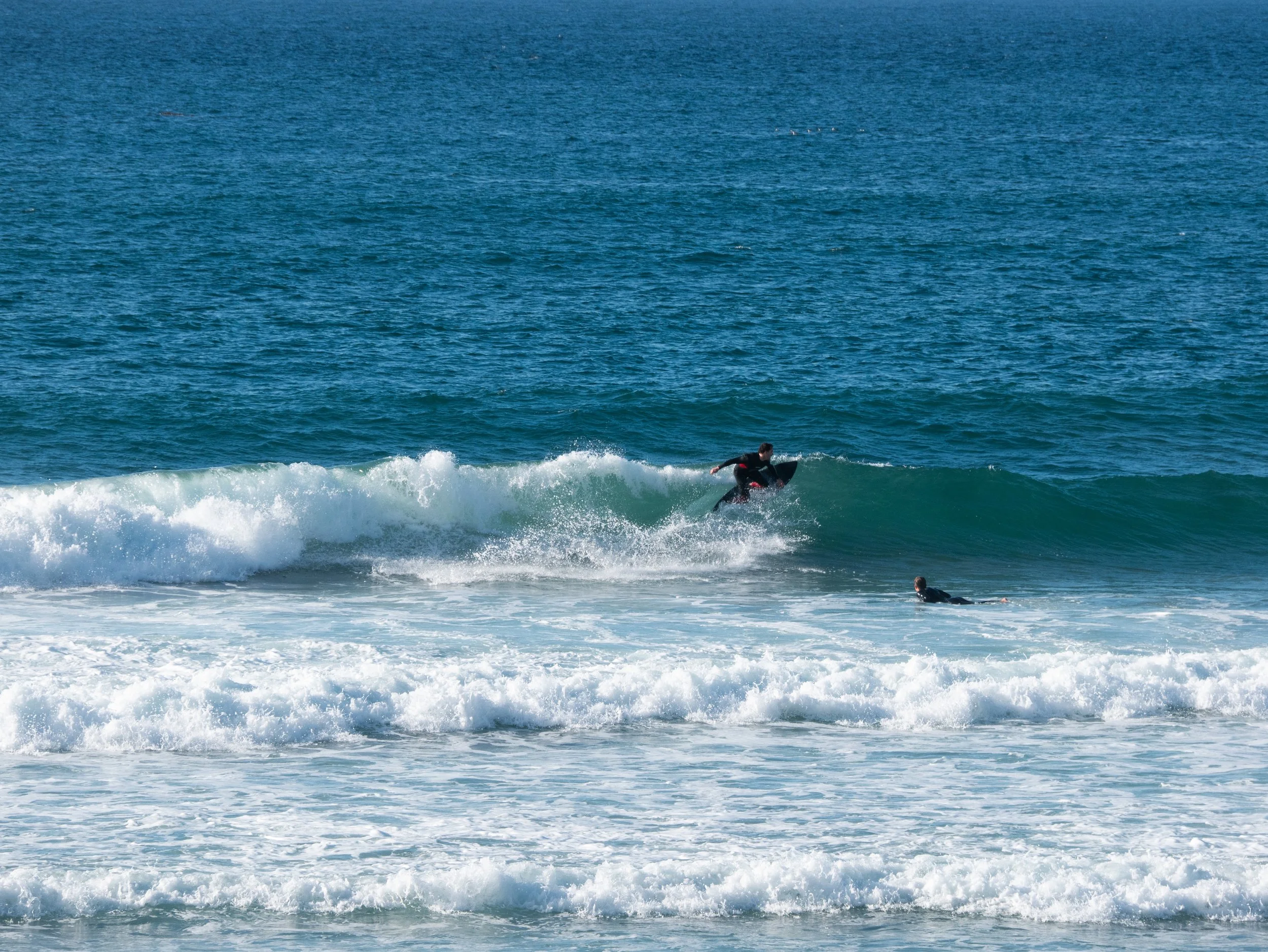 Two people surfing on the ocean waves.