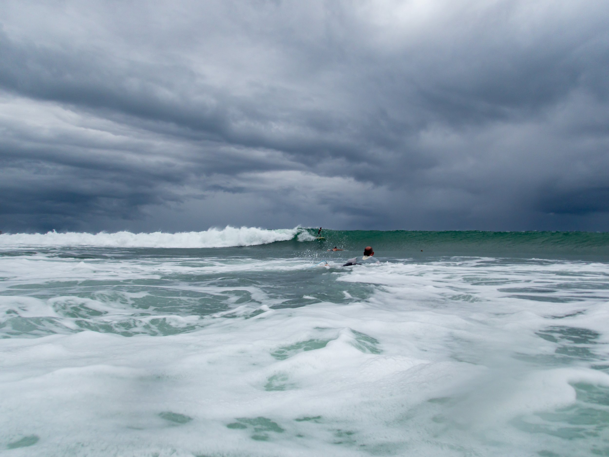 Ocean waves with cloudy sky and surfers