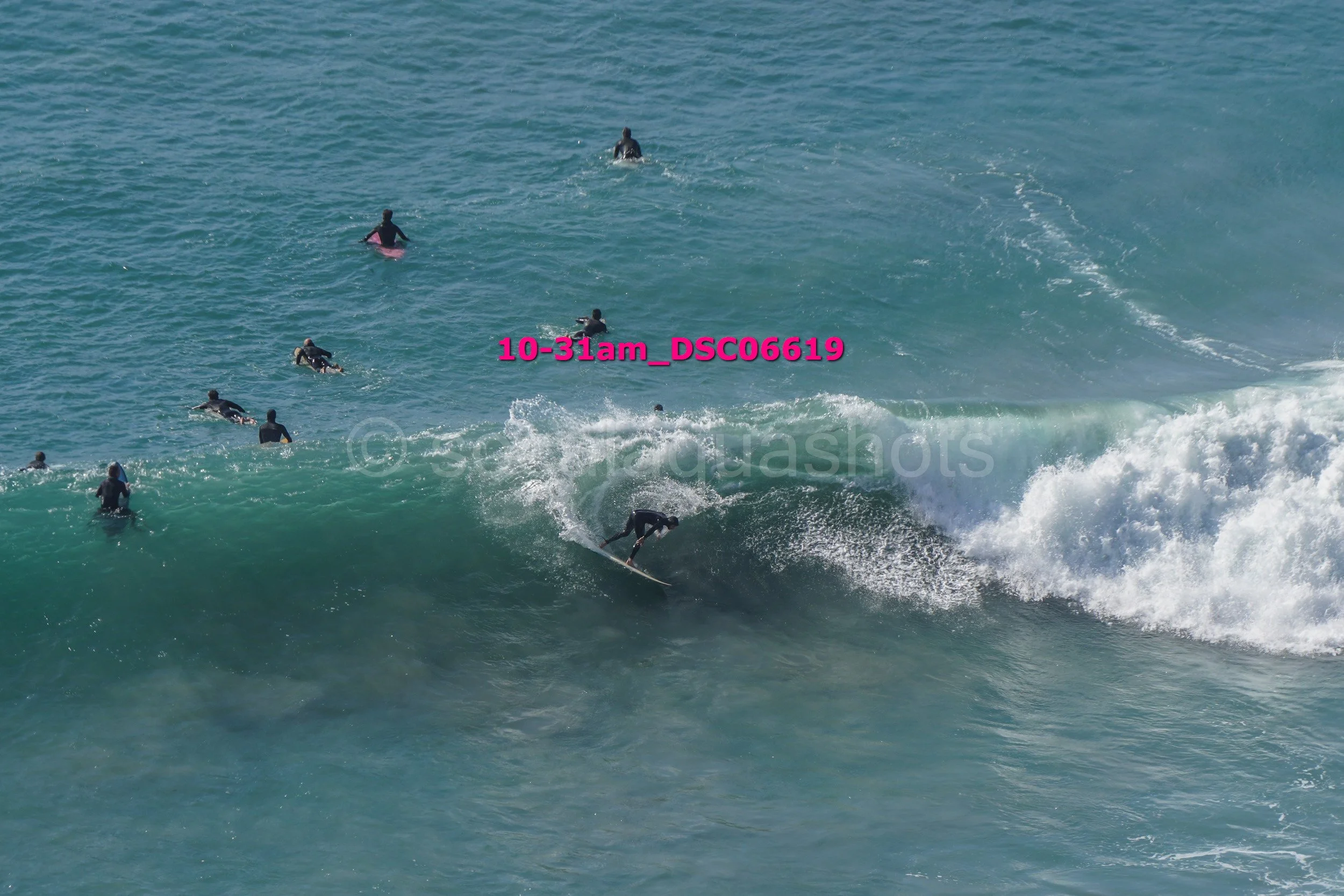 Surfer riding a wave with several surfers in the background in the ocean.
