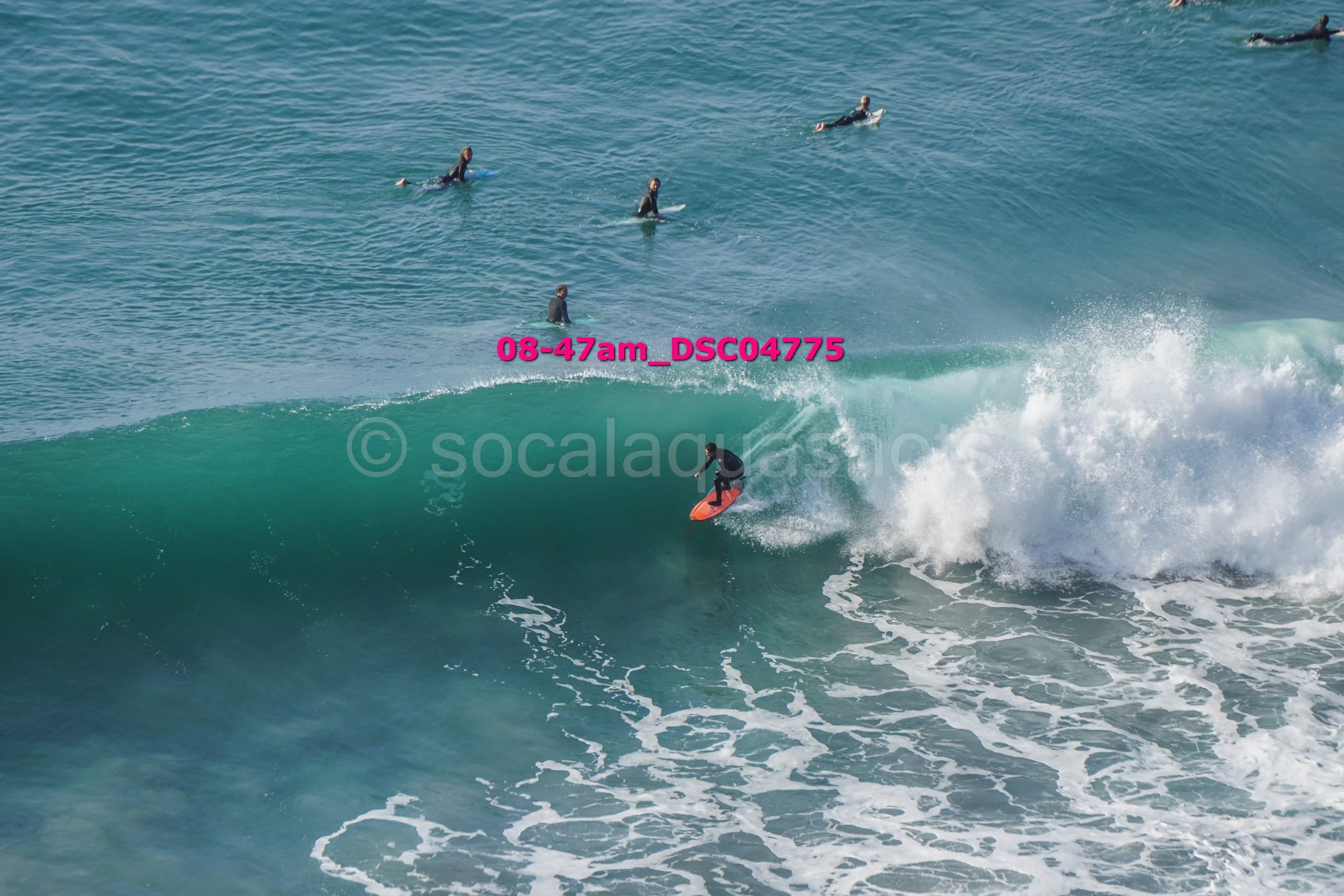 A person surfing on a wave with several surfers in the background