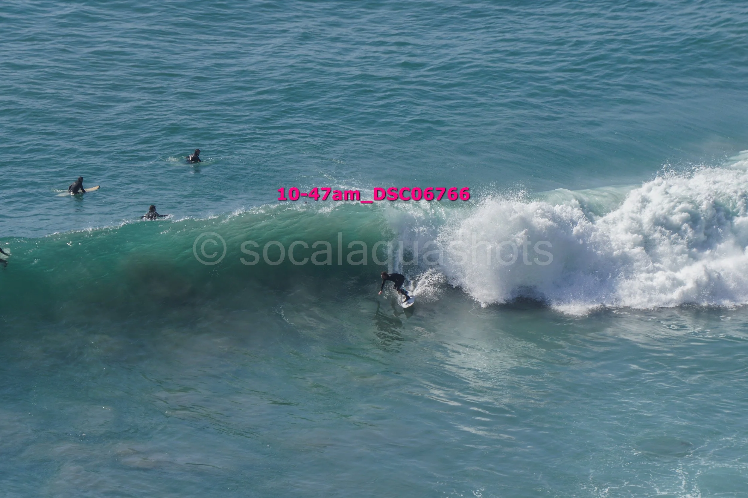 Surfer riding a wave with three surfers in the water nearby.