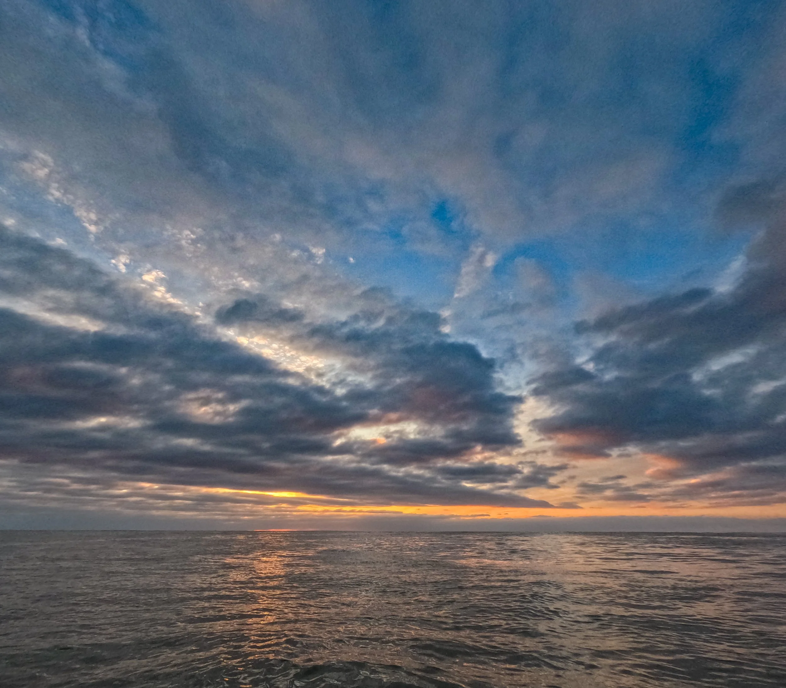 Sunset over the ocean with partly cloudy sky